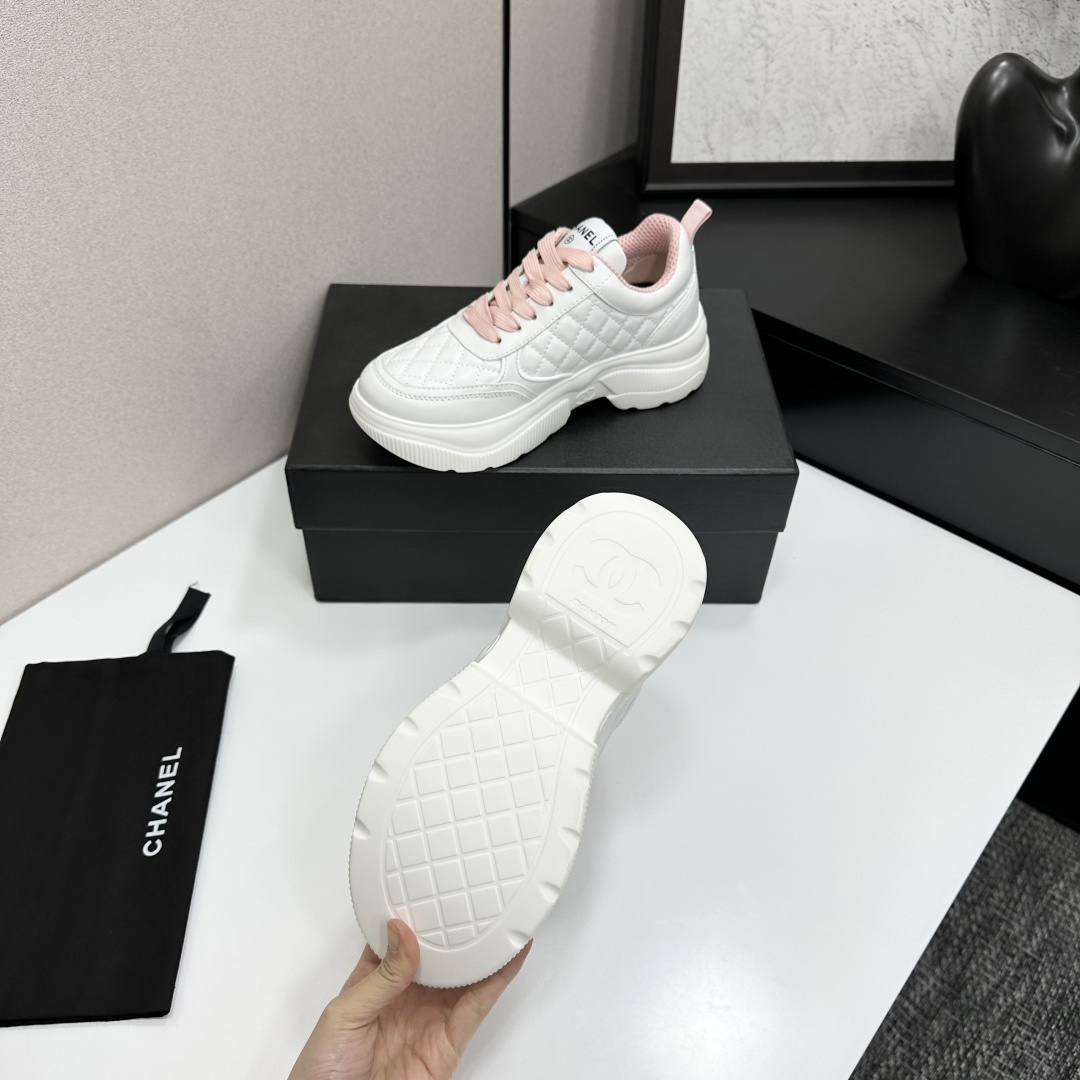 A pair of luxury Chanel white quilted platform sneakers with pink laces and pink interior lining displayed on a black box. - Hình 5
