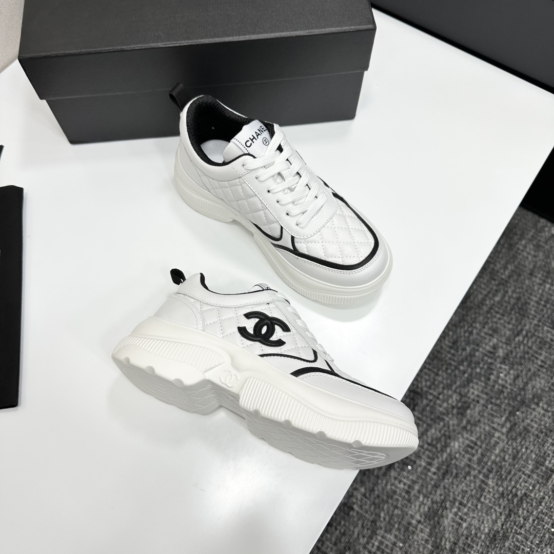 Side view of Chanel white quilted platform sneakers with black CC logo sitting on a branded black box. - Hình 9