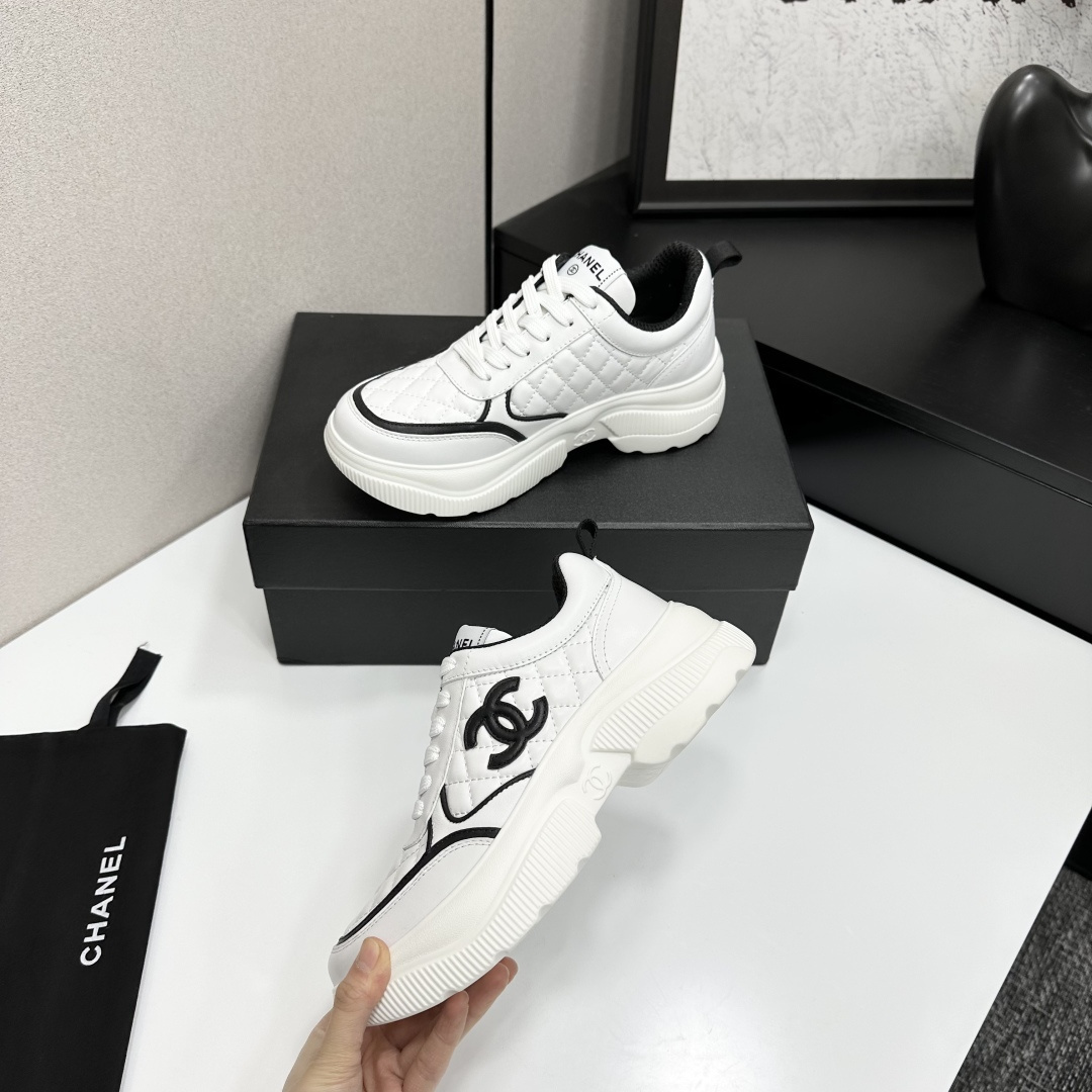 Side view of Chanel white quilted platform sneakers with black CC logo sitting on a branded black box. - Hình 4