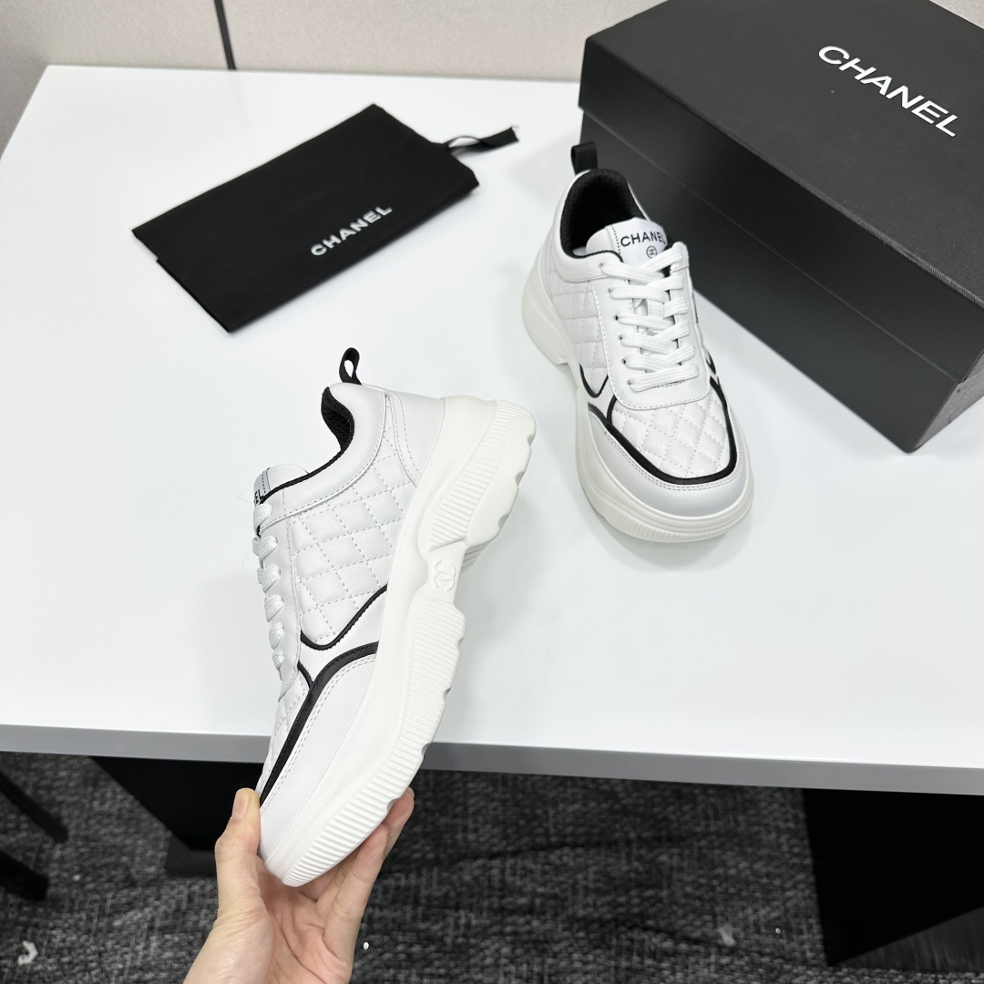Side view of Chanel white quilted platform sneakers with black CC logo sitting on a branded black box. - Hình 2