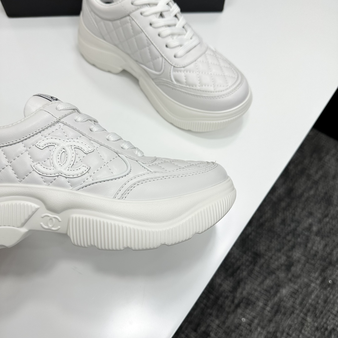 Side view of white Chanel quilted leather platform sneakers with interlocking C logo on a black display box - Hình 2