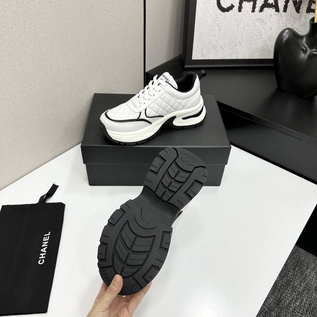 A pair of luxury Chanel white quilted leather sneakers with black CC logo and chunky white soles displayed on a black box. - Hình 5