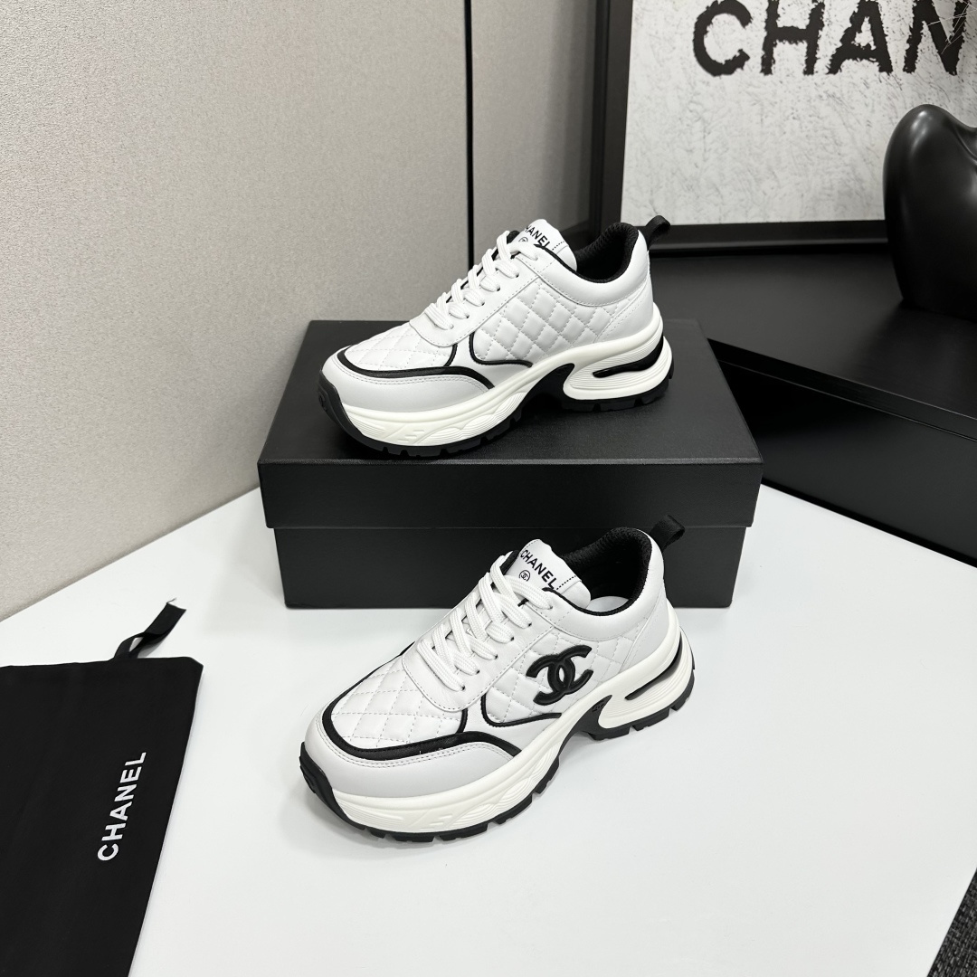 A pair of luxury Chanel white quilted leather sneakers with black CC logo and chunky white soles displayed on a black box. - Hình 3
