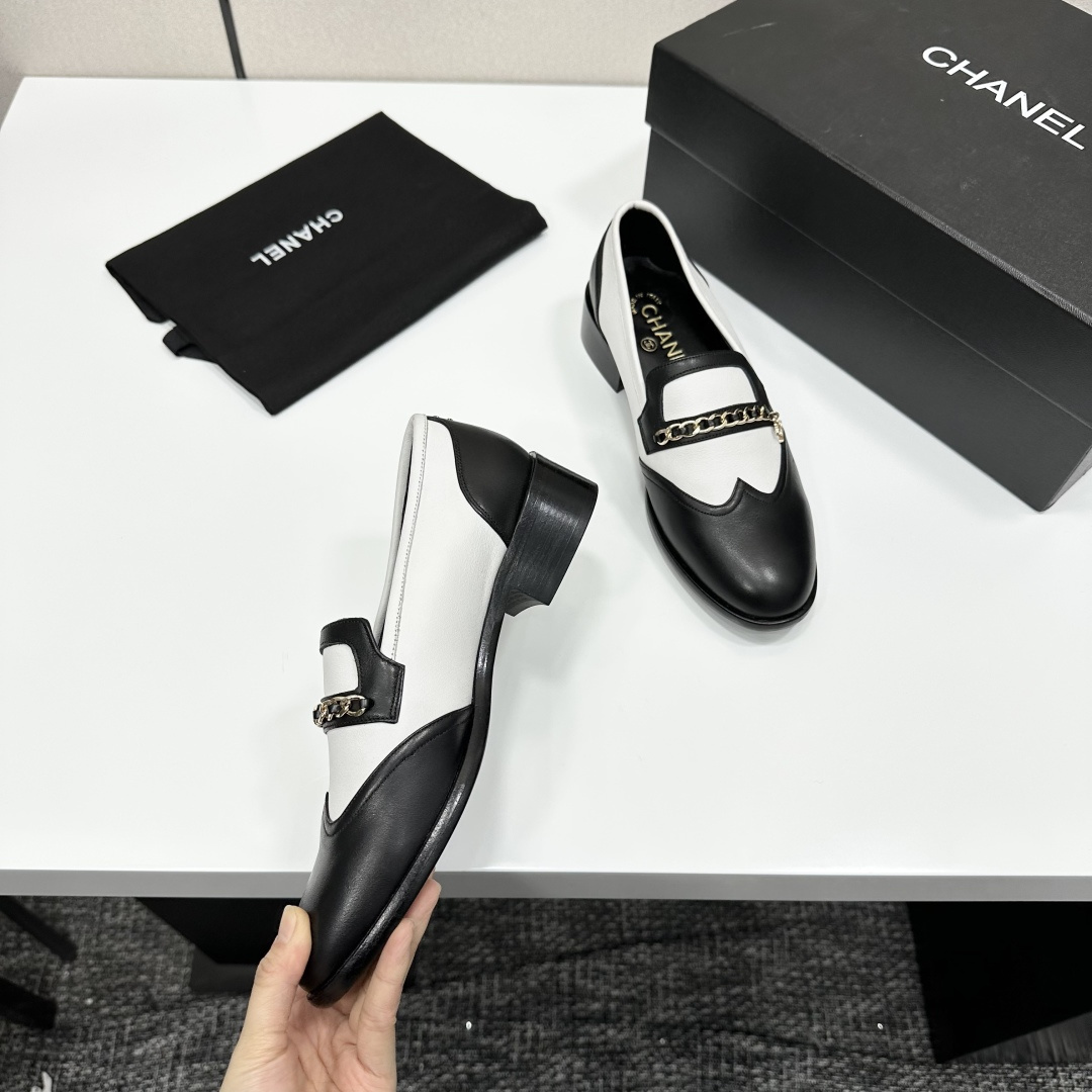 Pair of Chanel black and white two-tone leather loafers with gold chain detail on a black box - Hình 10