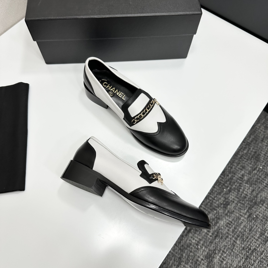 Pair of Chanel black and white two-tone leather loafers with gold chain detail on a black box - Hình 9