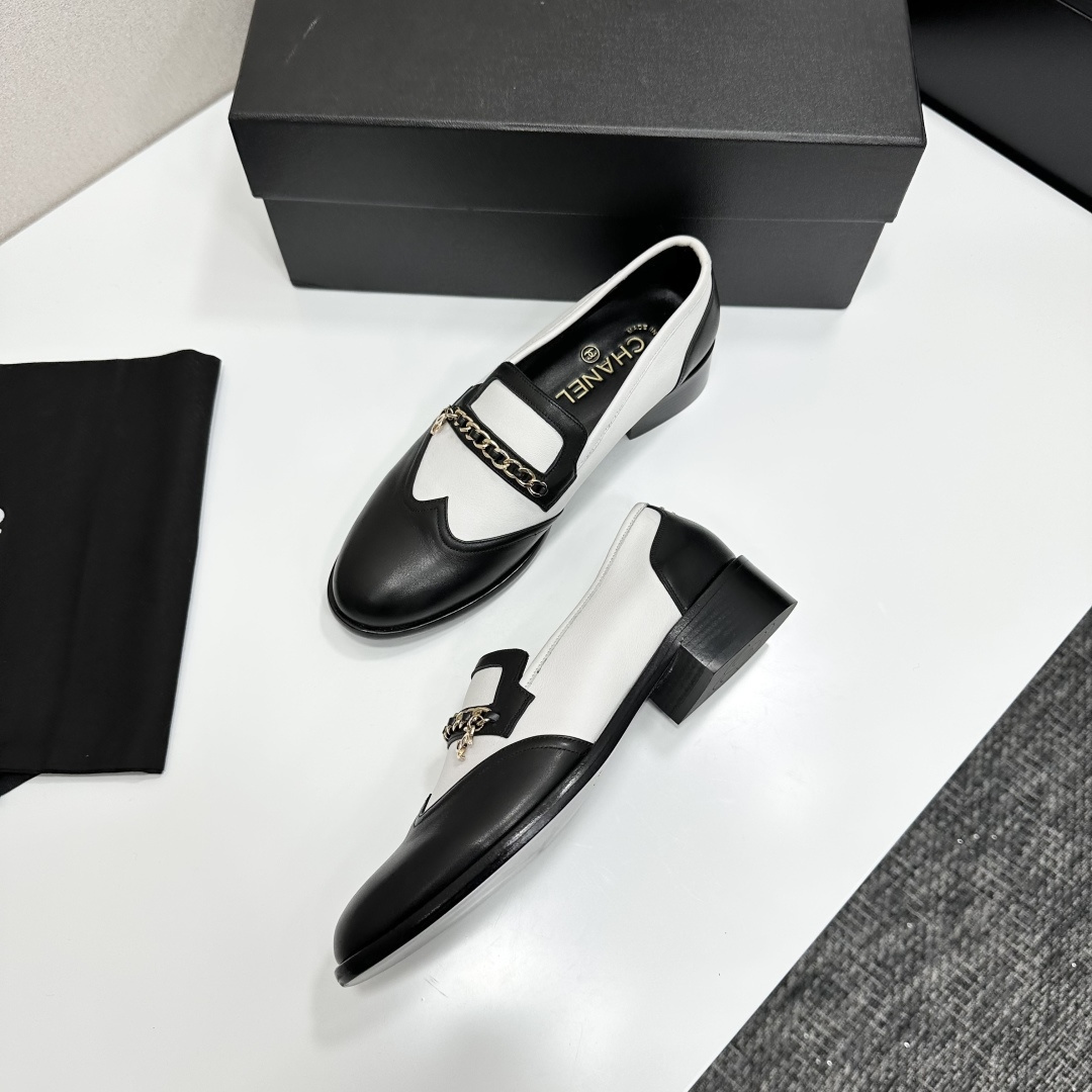 Pair of Chanel black and white two-tone leather loafers with gold chain detail on a black box - Hình 7