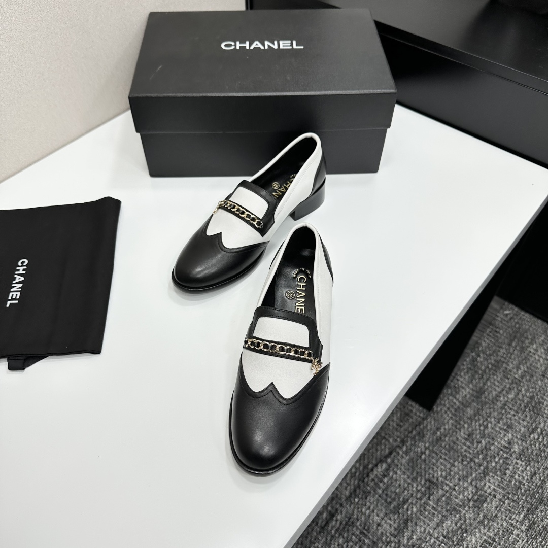 Pair of Chanel black and white two-tone leather loafers with gold chain detail on a black box - Hình 6