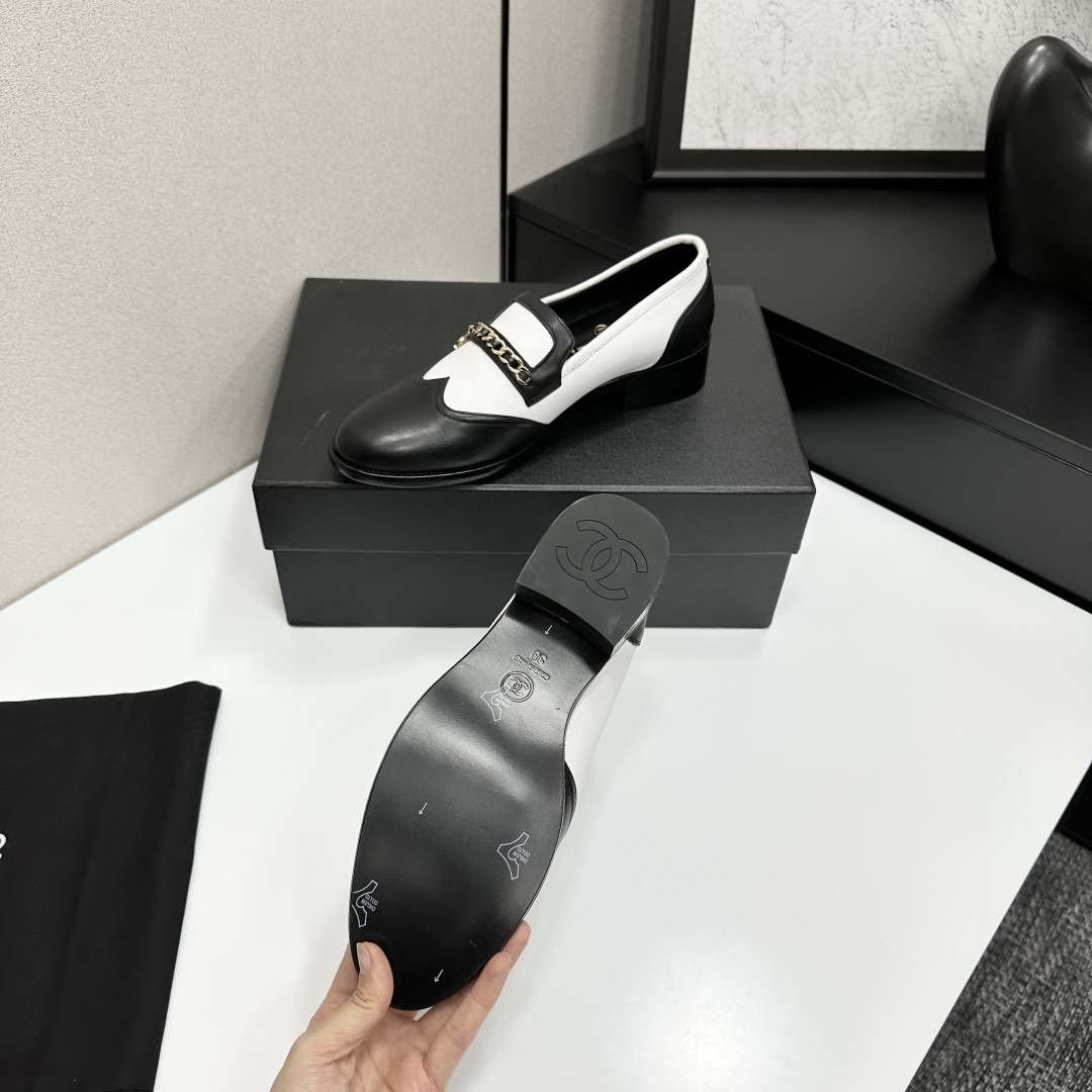 Pair of Chanel black and white two-tone leather loafers with gold chain detail on a black box - Hình 5