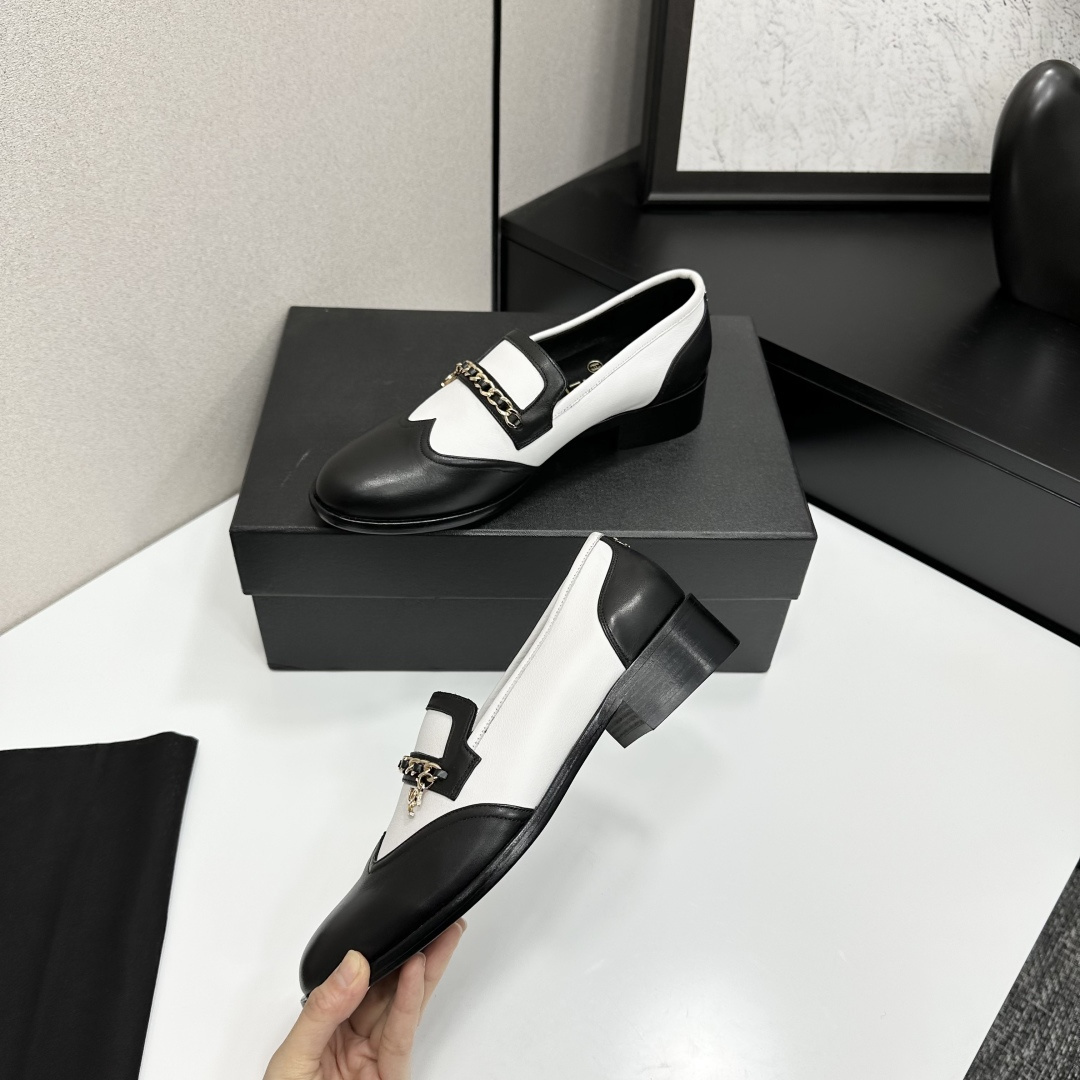 Pair of Chanel black and white two-tone leather loafers with gold chain detail on a black box - Hình 4
