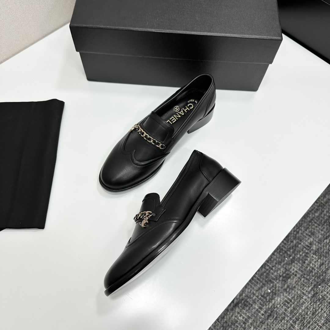 Classic black leather loafers with a gold chain and interlocking CC logo detail resting on a black shoebox. - Hình 6