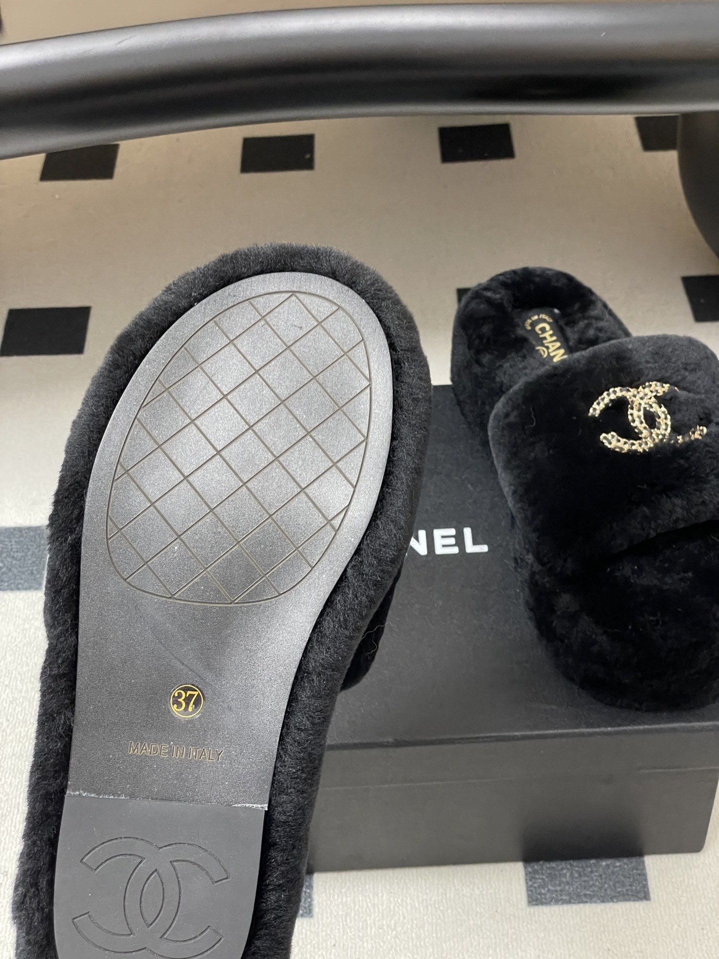 Pair of black Chanel shearling platform slides with gold chain interlocking CC logo on a black table. - Hình 8