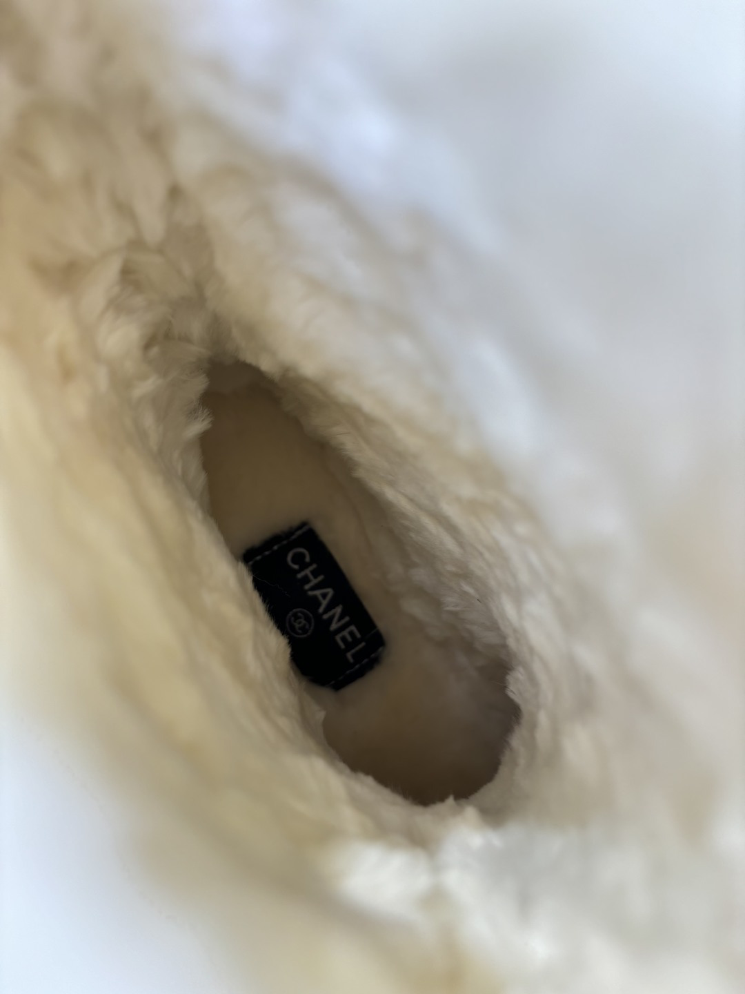 A pair of black suede winter boots with white faux fur trim and a circular fur logo on a white surface - Hình 9