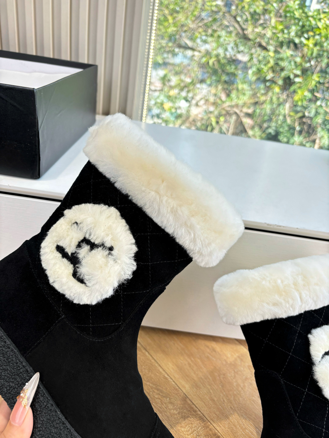 A pair of black suede winter boots with white faux fur trim and a circular fur logo on a white surface - Hình 8