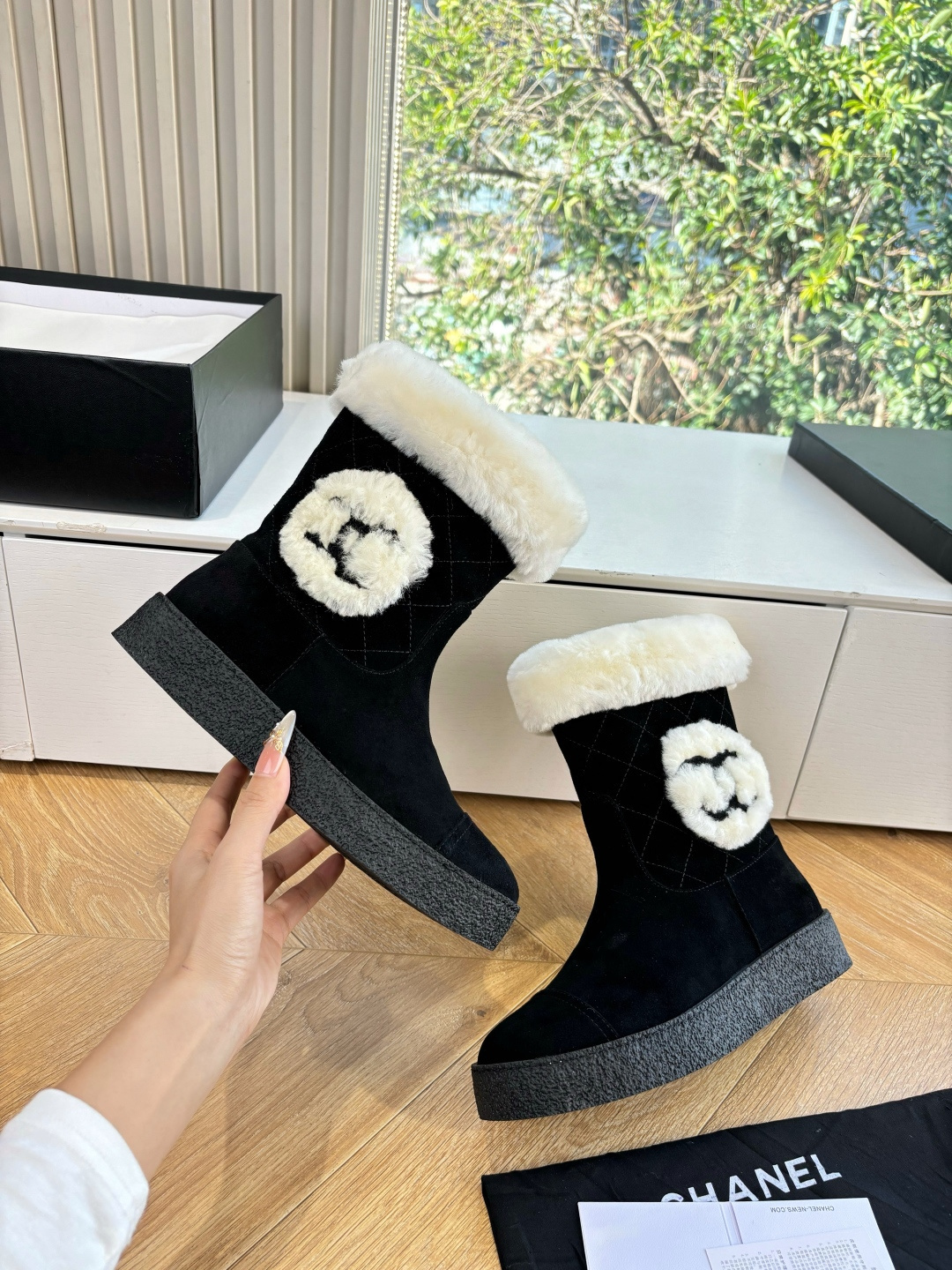A pair of black suede winter boots with white faux fur trim and a circular fur logo on a white surface - Hình 7
