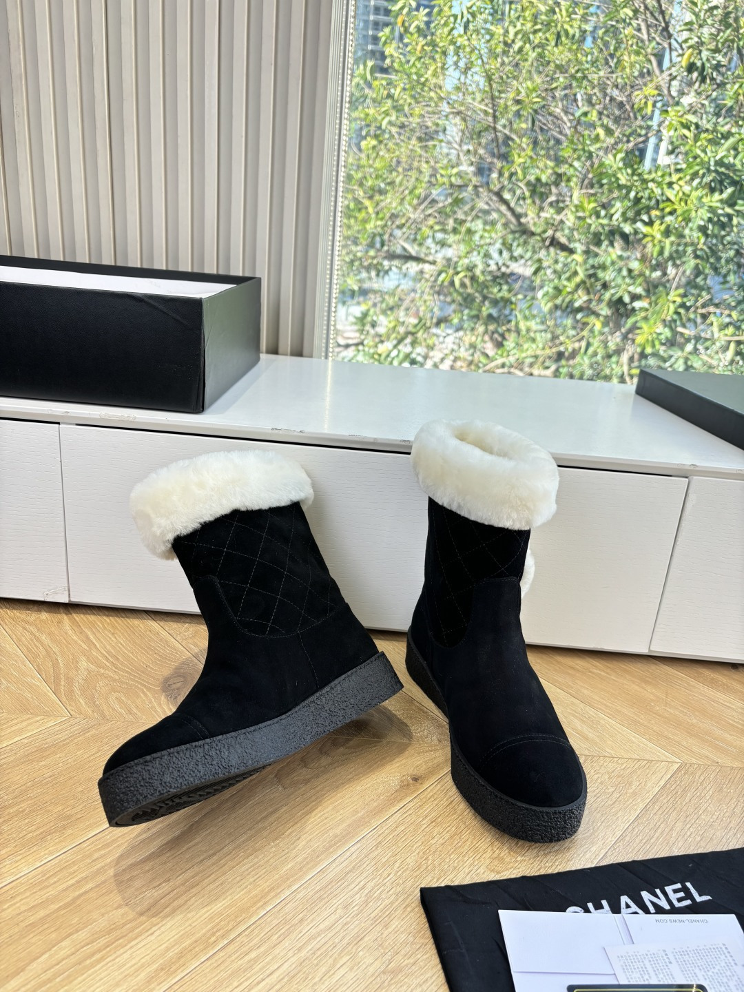 A pair of black suede winter boots with white faux fur trim and a circular fur logo on a white surface - Hình 6