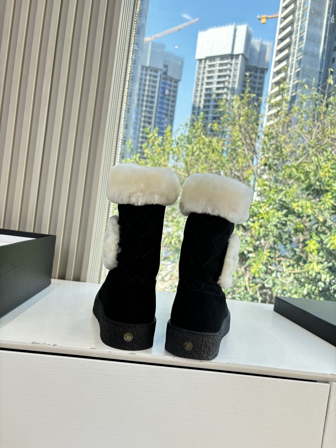 A pair of black suede winter boots with white faux fur trim and a circular fur logo on a white surface - Hình 4