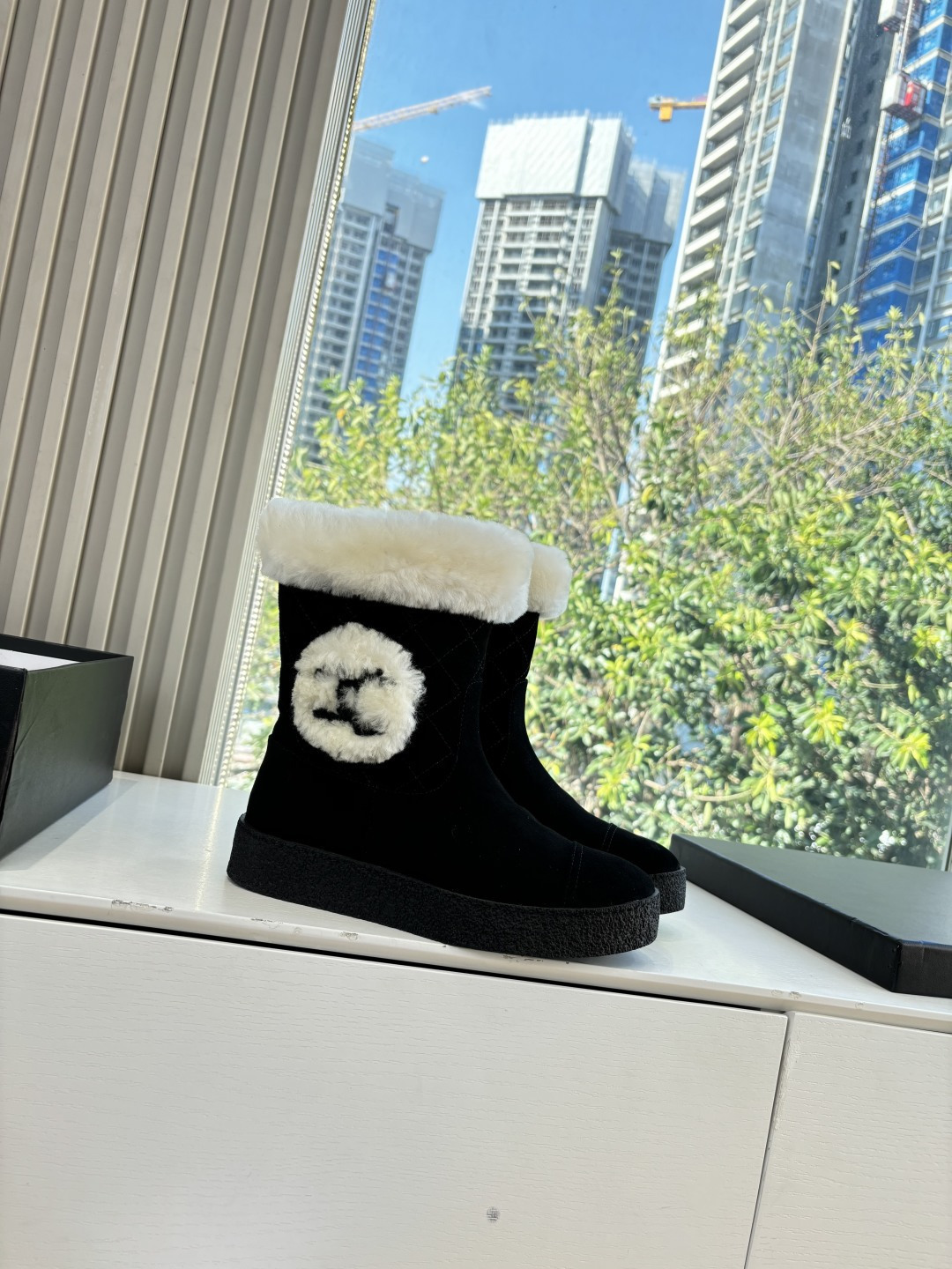 A pair of black suede winter boots with white faux fur trim and a circular fur logo on a white surface - Hình 3