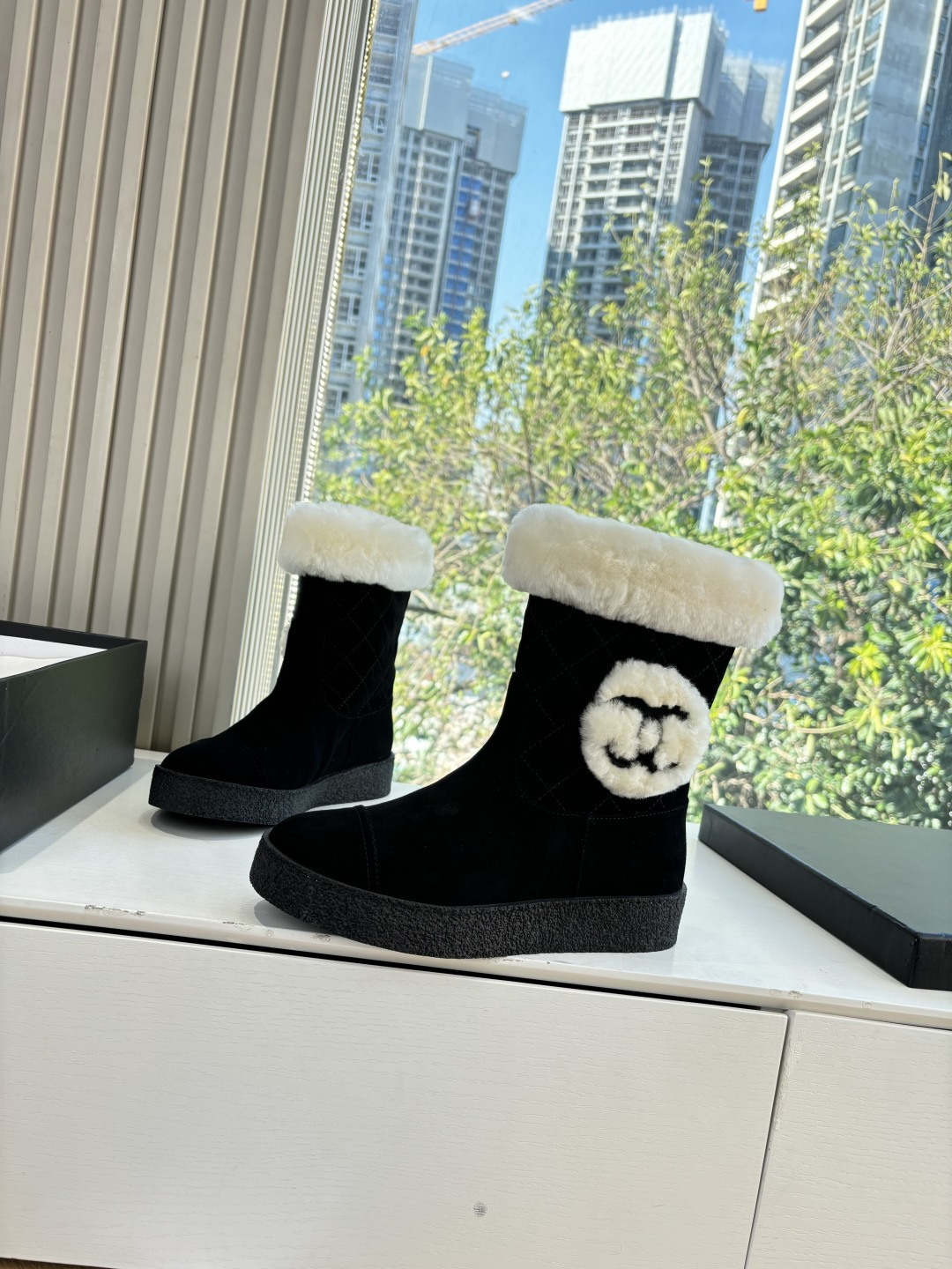 A pair of black suede winter boots with white faux fur trim and a circular fur logo on a white surface - Hình 2