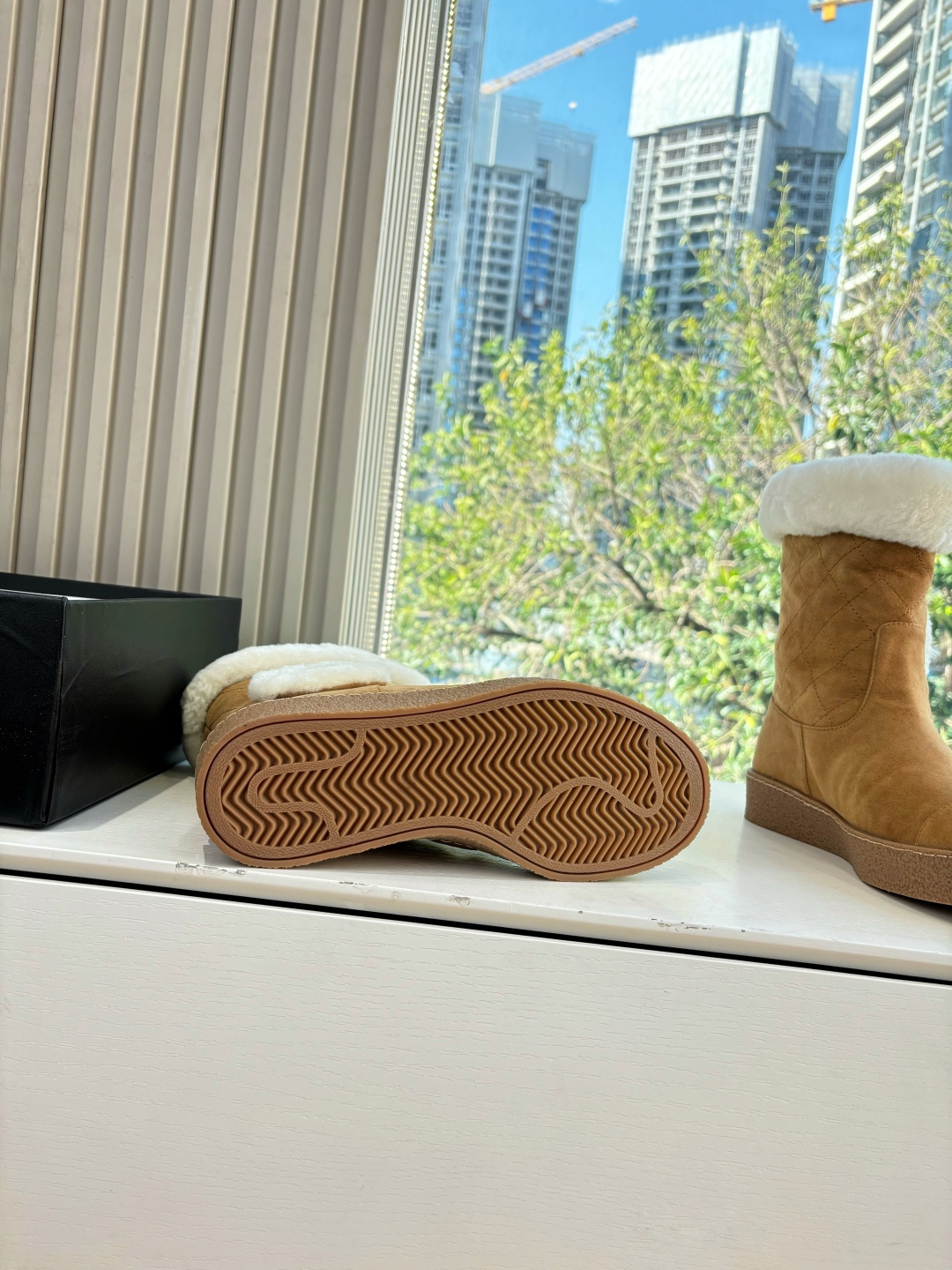 A pair of luxury tan suede winter boots with white shearling trim and a plush logo patch displayed on a white surface. - Hình 9