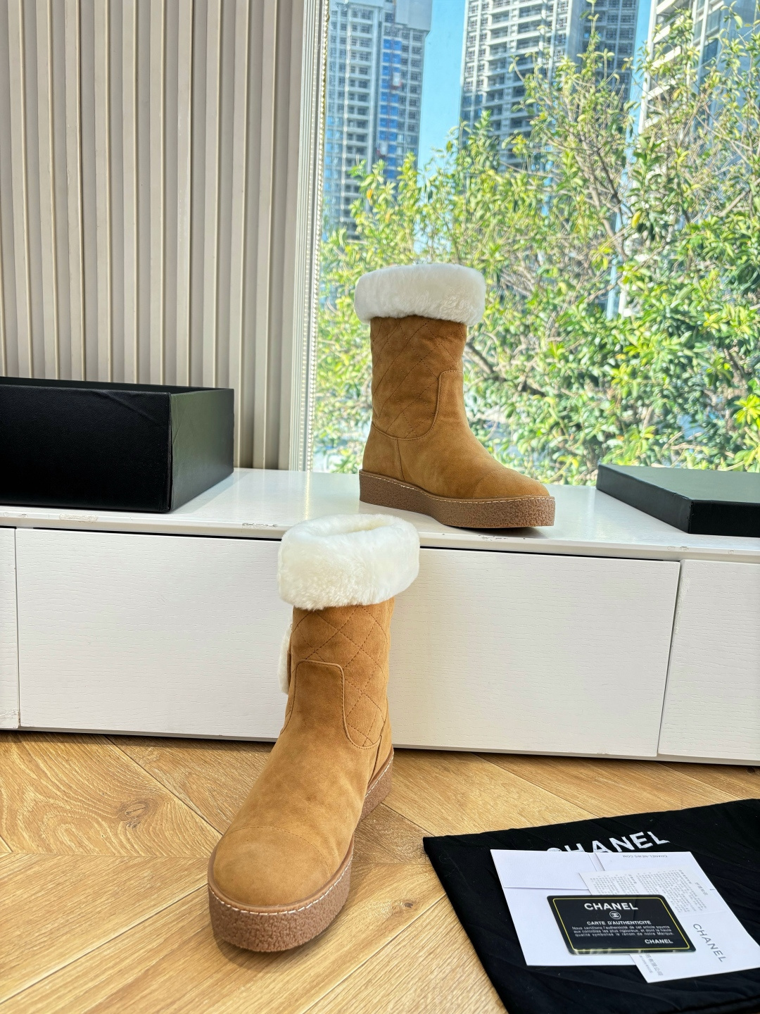 A pair of luxury tan suede winter boots with white shearling trim and a plush logo patch displayed on a white surface. - Hình 5