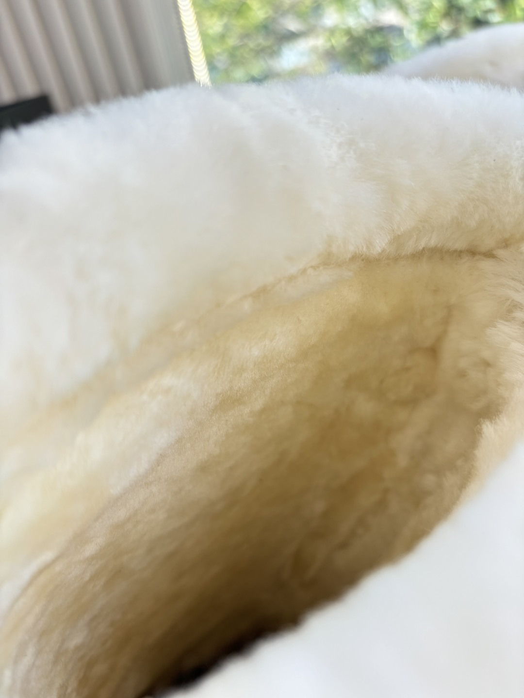 Pair of camel-colored quilted suede tall boots with white faux fur trim and circular logo detail on a white surface - Hình 9