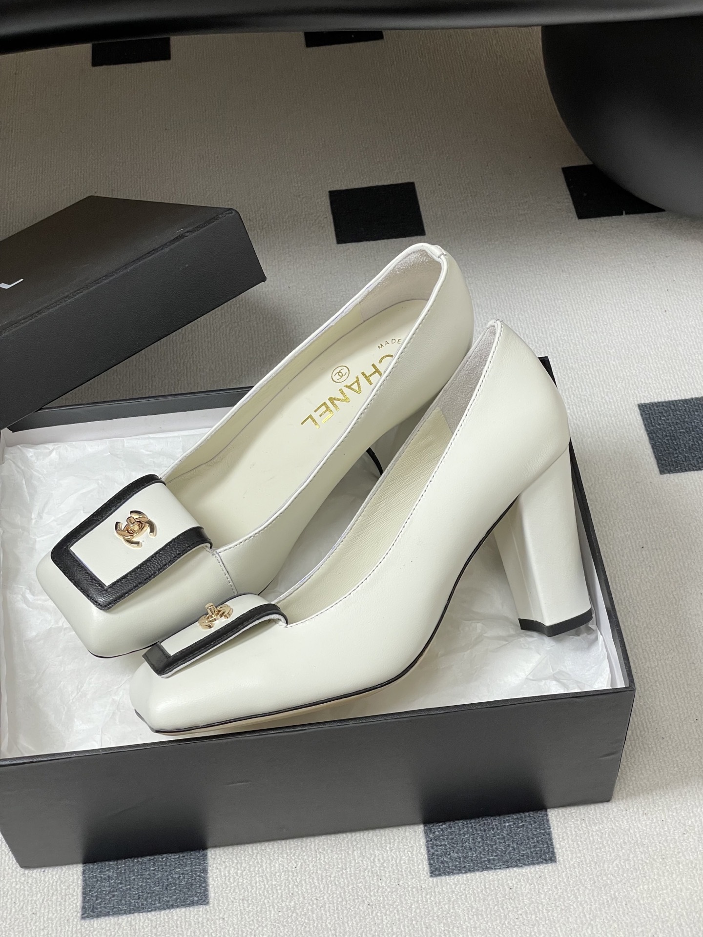 Pair of Chanel white leather square toe pumps with black trim and gold CC logo on a black surface. - Hình 4