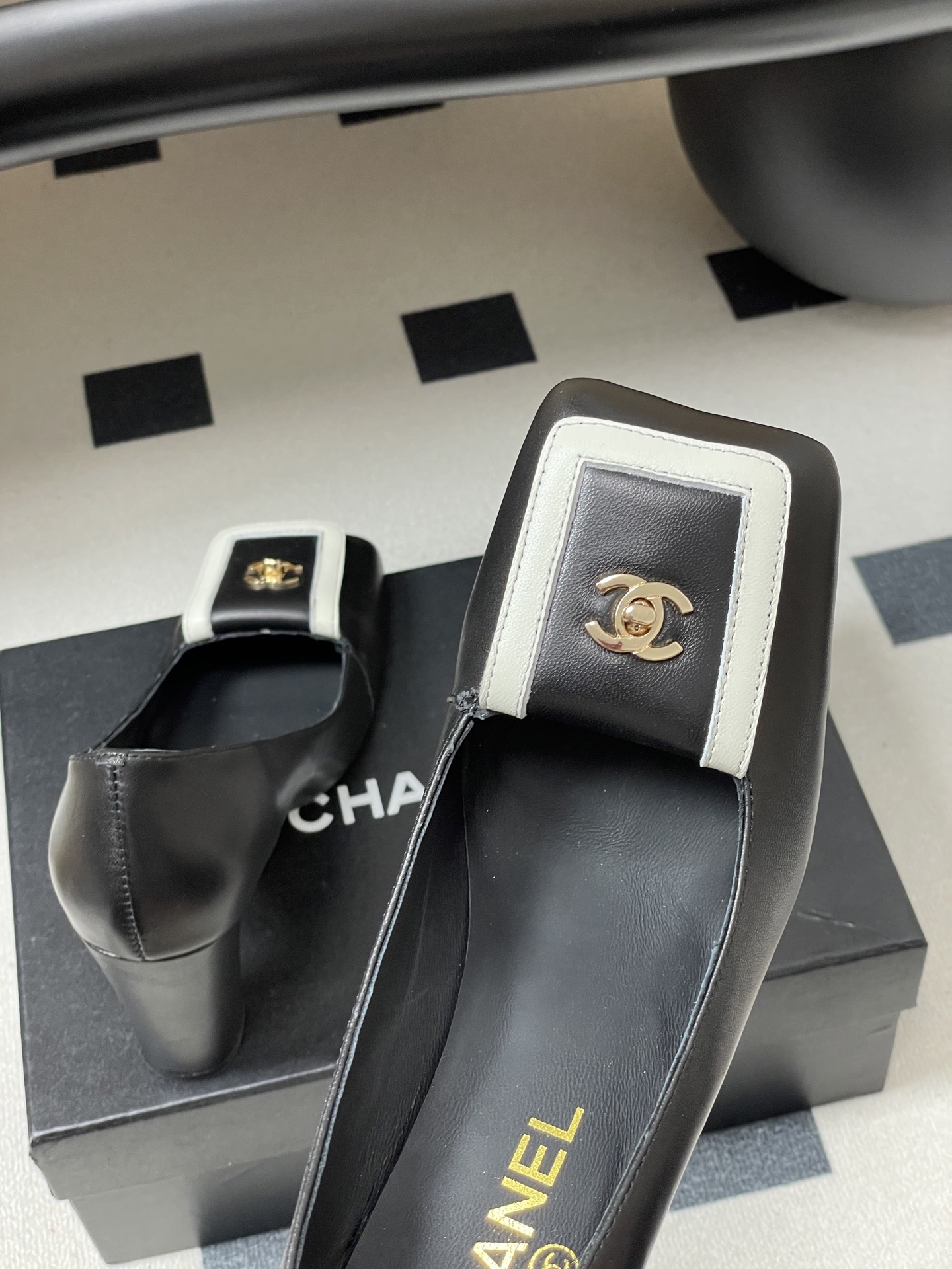 A pair of Chanel black leather block heel pumps with square toes and gold-tone CC logos on white buckle details. - Hình 9