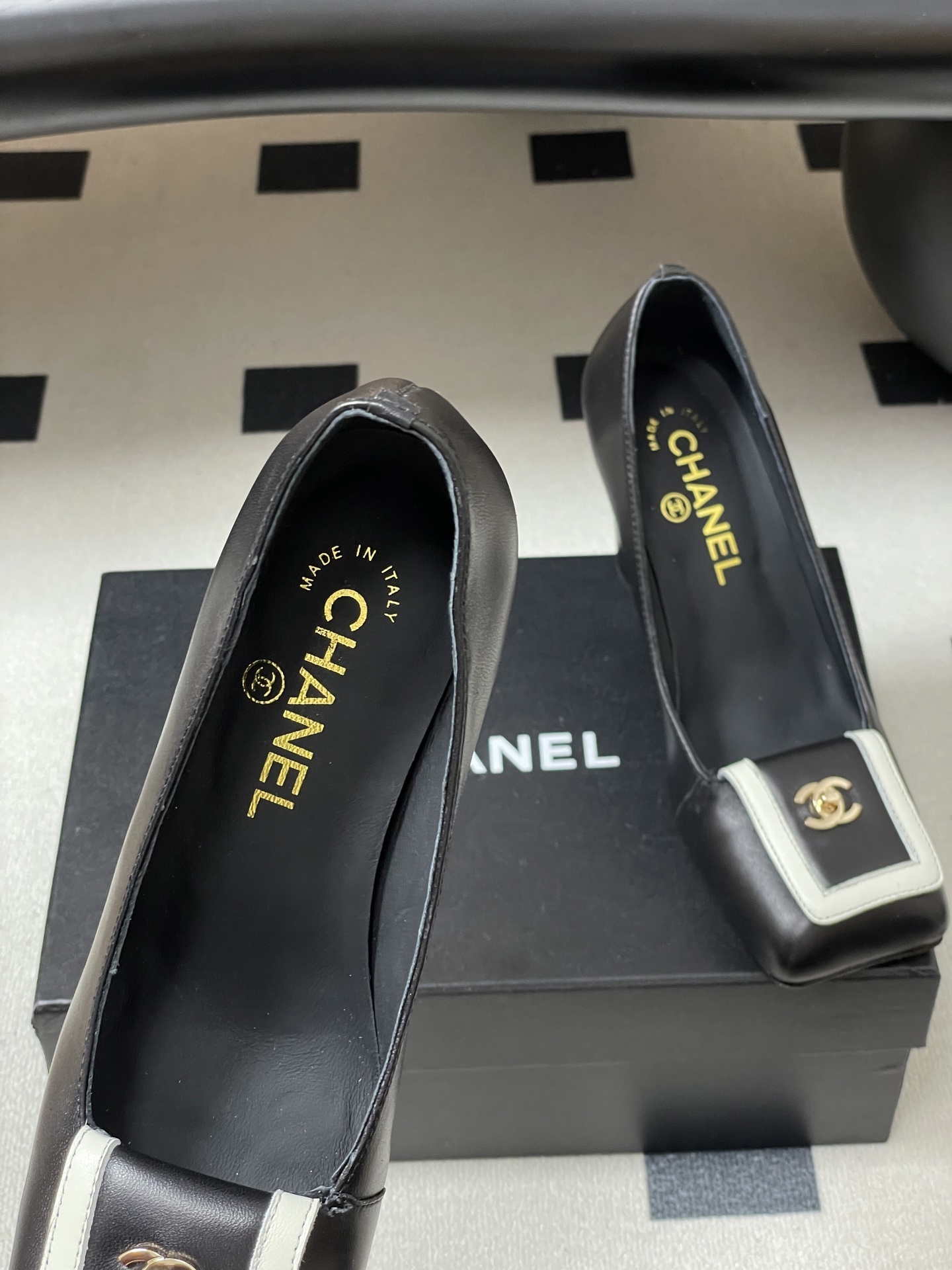 A pair of Chanel black leather block heel pumps with square toes and gold-tone CC logos on white buckle details. - Hình 7
