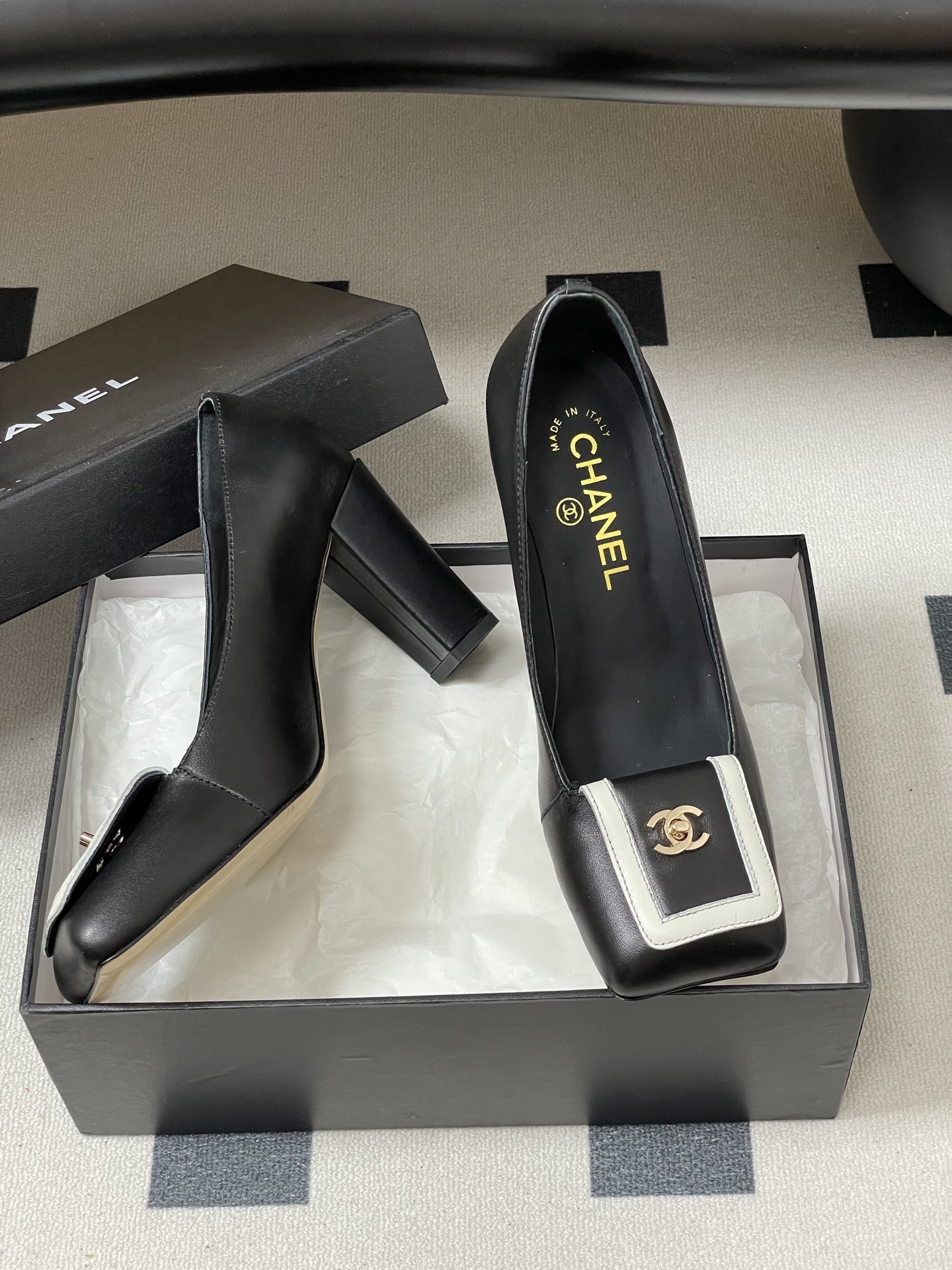 A pair of Chanel black leather block heel pumps with square toes and gold-tone CC logos on white buckle details. - Hình 6