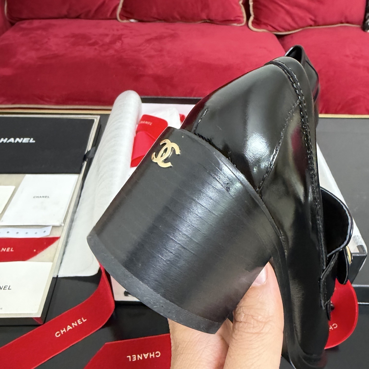 Luxury black Chanel patent leather loafers with gold CC logo buttons displayed in a box with red ribbons - Hình 8