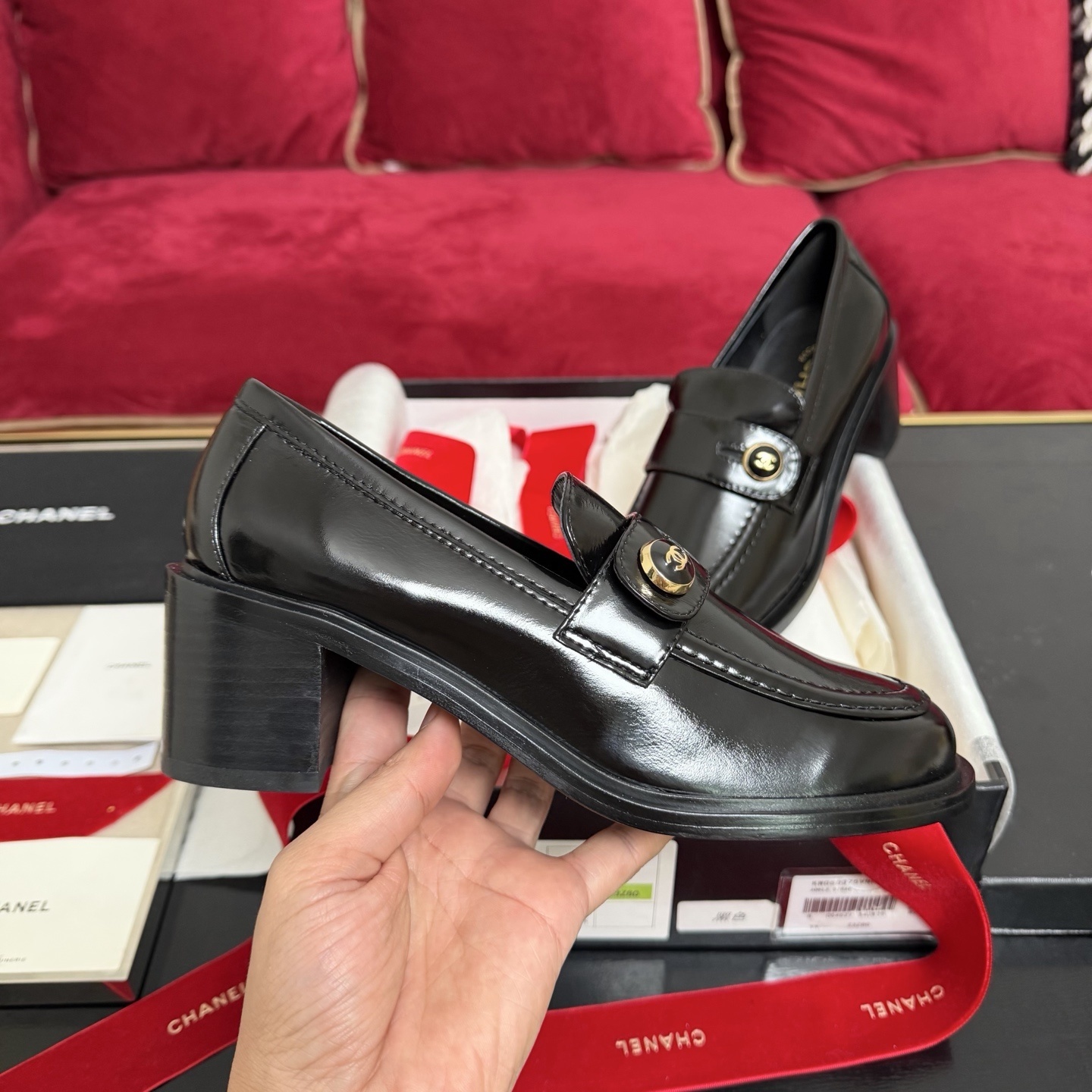 Luxury black Chanel patent leather loafers with gold CC logo buttons displayed in a box with red ribbons - Hình 5
