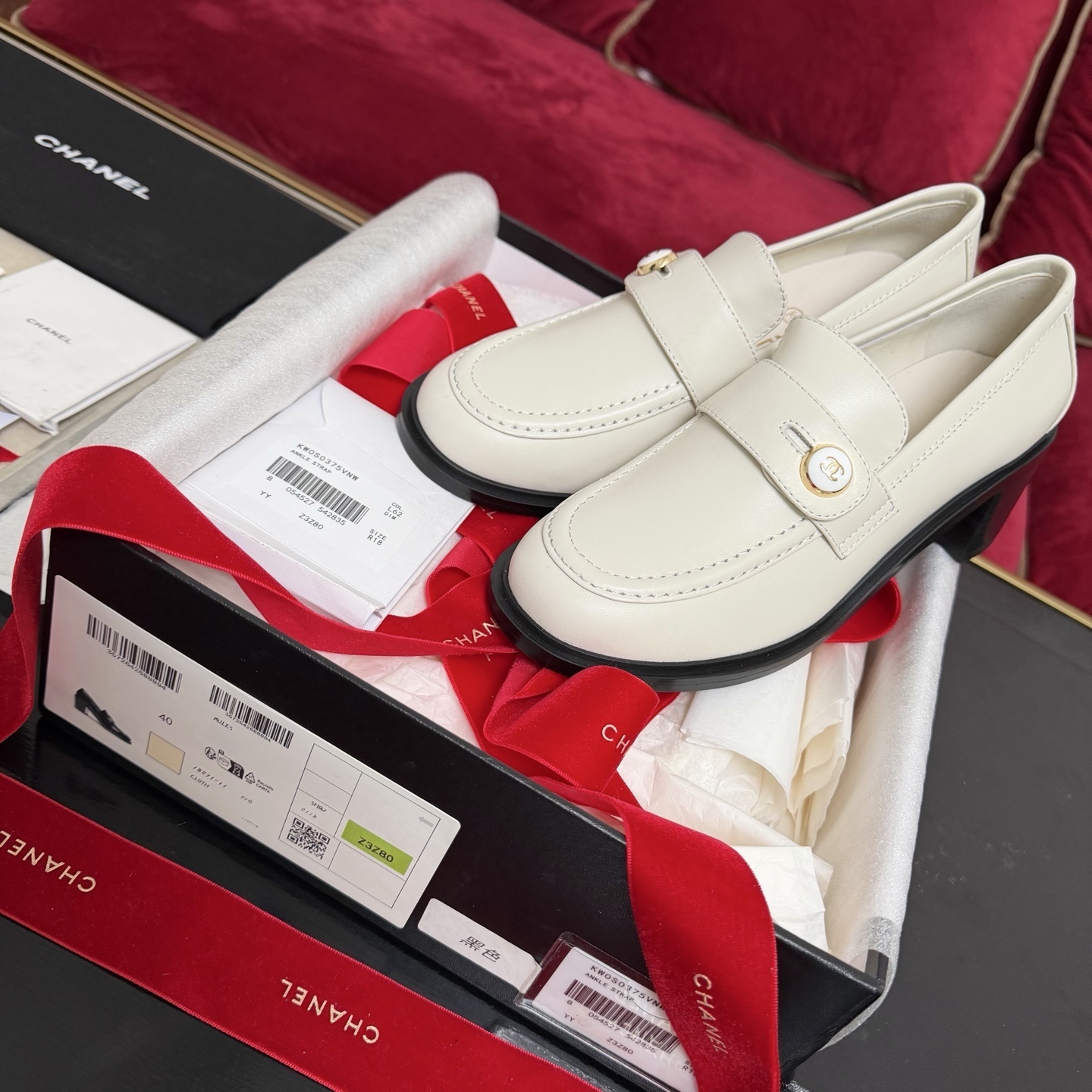 Pair of cream Chanel leather loafers with gold CC logo button and black block heel in original luxury packaging - Hình 2