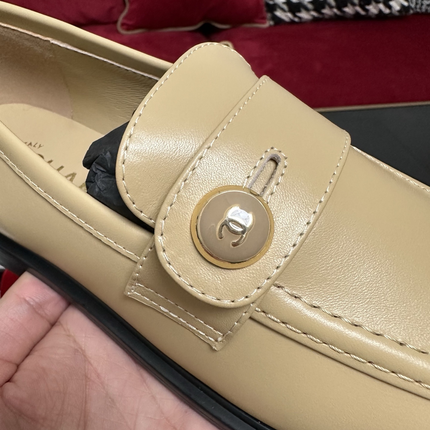 A pair of Chanel beige leather loafers with gold CC logo buttons presented in a luxury black box with red ribbons. - Hình 7