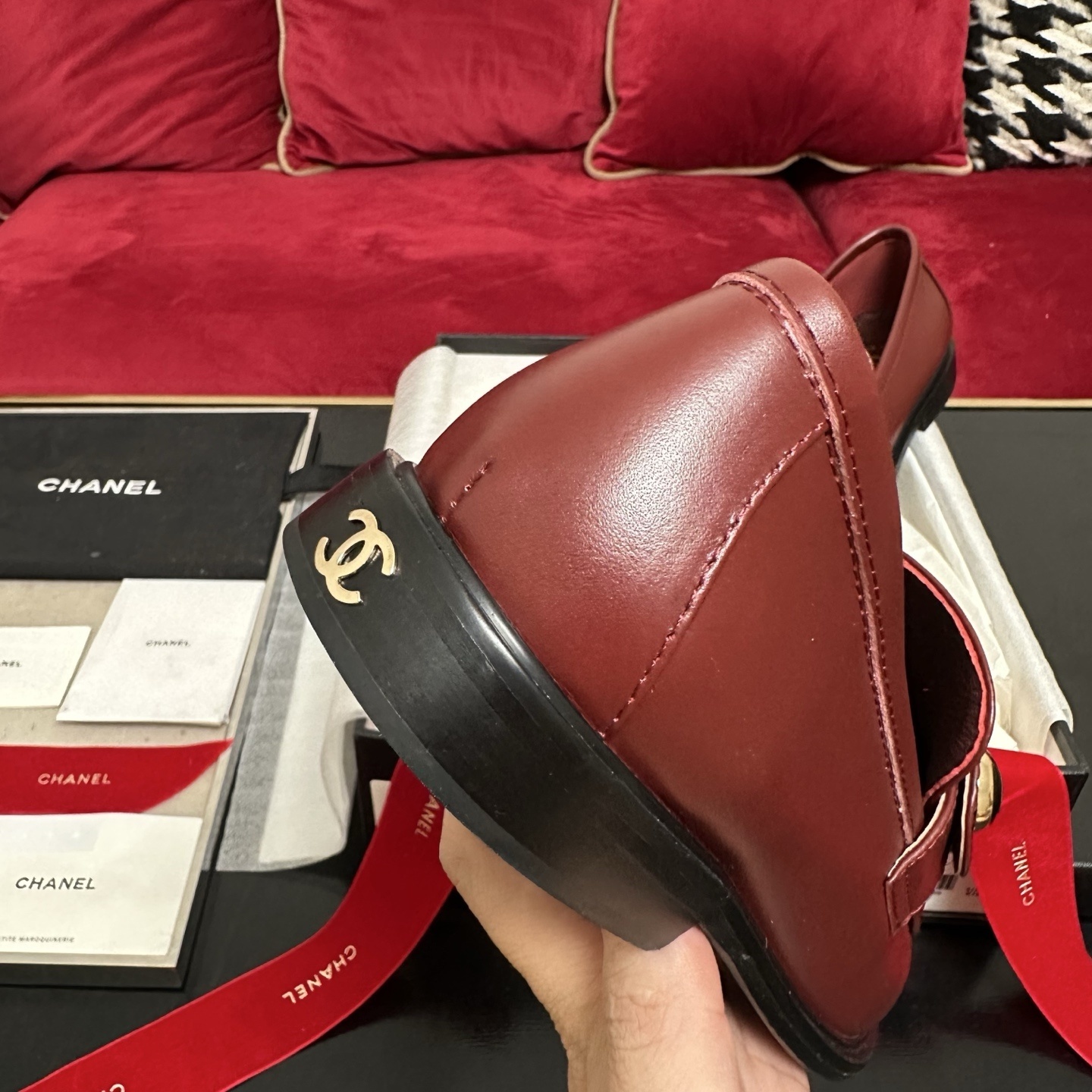 Luxury Chanel burgundy leather loafers with gold CC logo button displayed with designer packaging and red ribbons - Hình 8