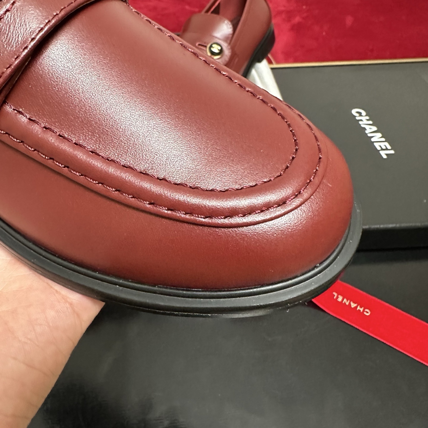 Luxury Chanel burgundy leather loafers with gold CC logo button displayed with designer packaging and red ribbons - Hình 6