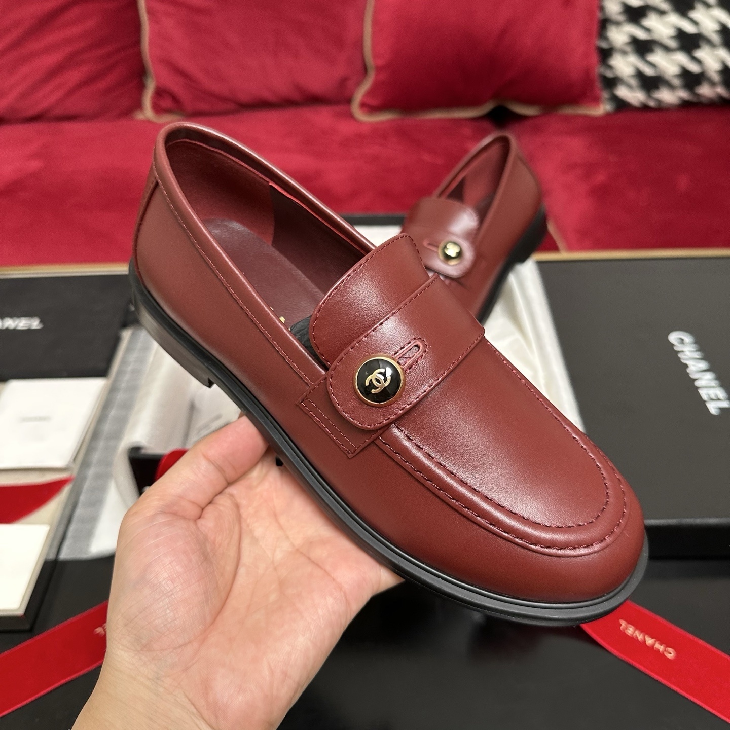 Luxury Chanel burgundy leather loafers with gold CC logo button displayed with designer packaging and red ribbons - Hình 4