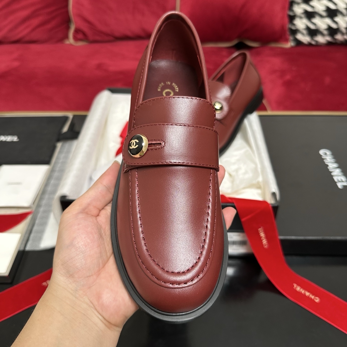 Luxury Chanel burgundy leather loafers with gold CC logo button displayed with designer packaging and red ribbons - Hình 3