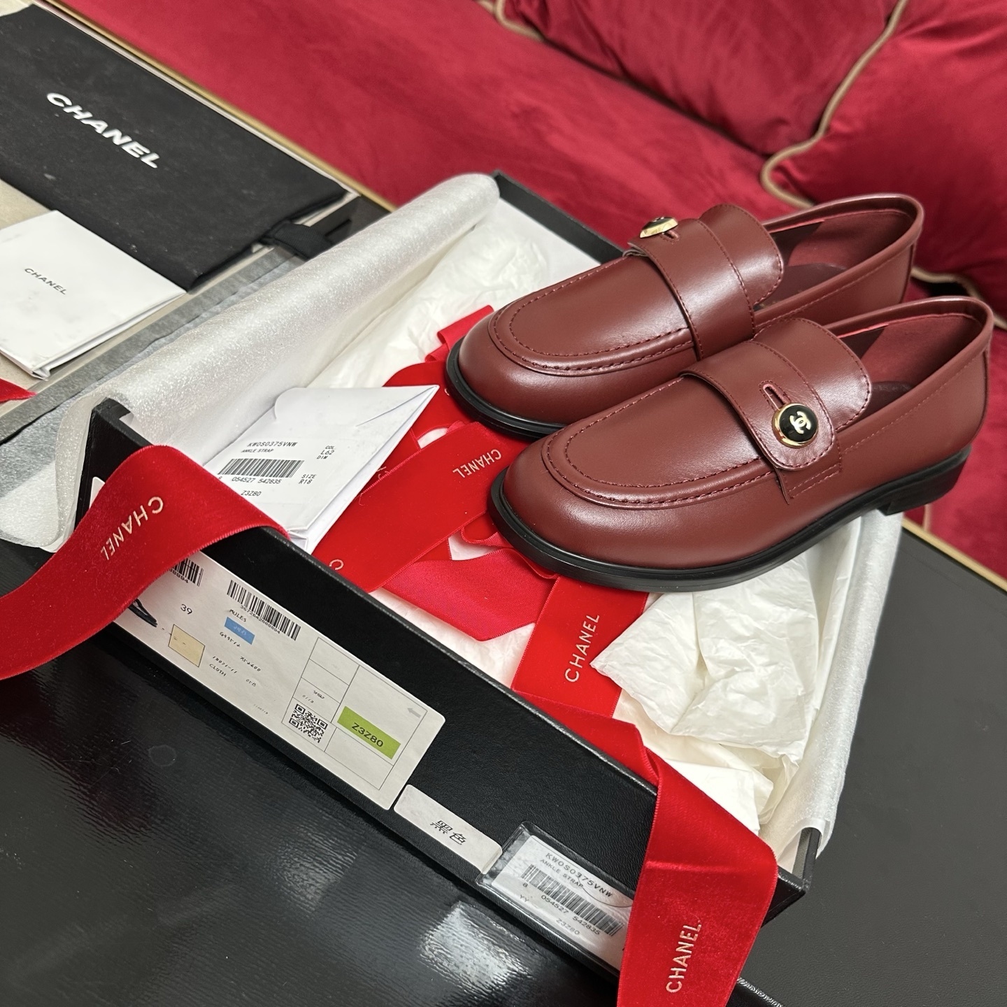 Luxury Chanel burgundy leather loafers with gold CC logo button displayed with designer packaging and red ribbons - Hình 2