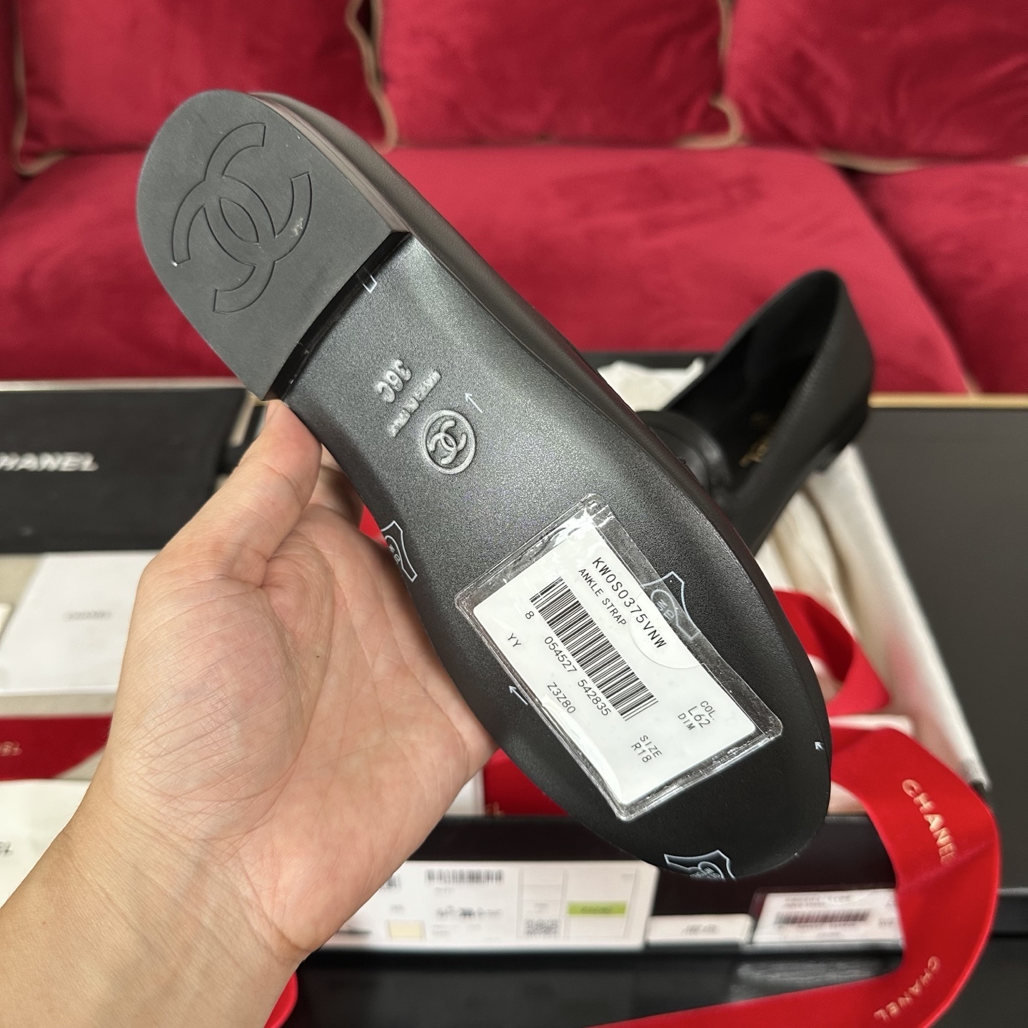 Pair of black Chanel leather loafers with gold CC logo on a decorative background with red ribbons and original box. - Hình 9