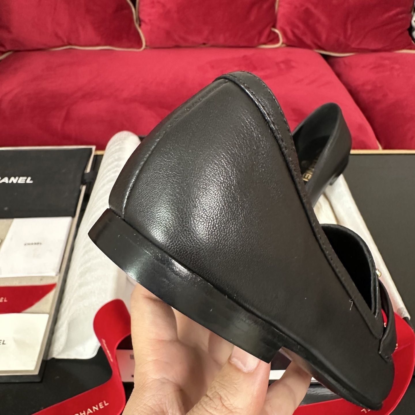 Pair of black Chanel leather loafers with gold CC logo on a decorative background with red ribbons and original box. - Hình 8