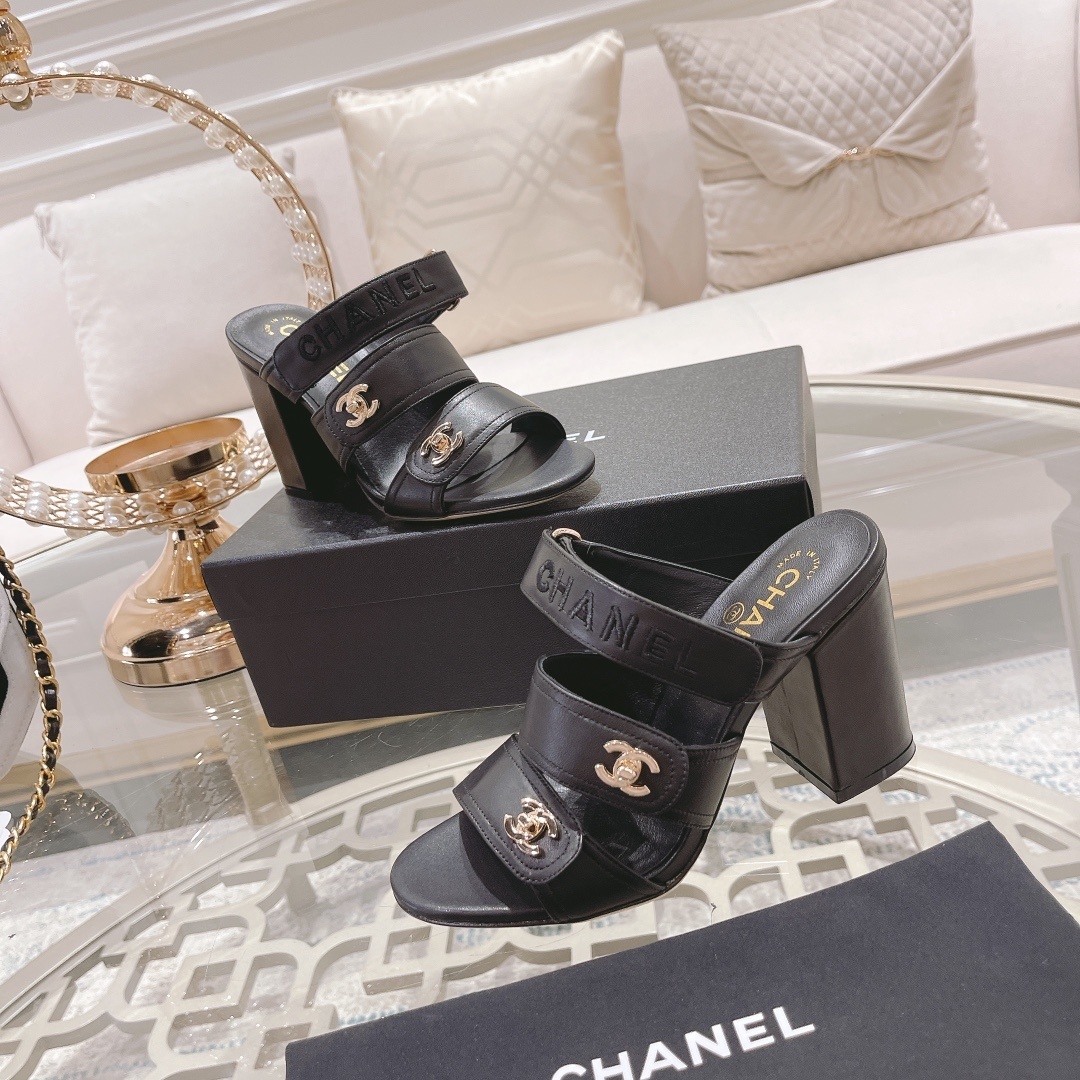 A pair of luxury Chanel black leather triple strap block heel mules with gold CC logos displayed on a glass table - Hình 6