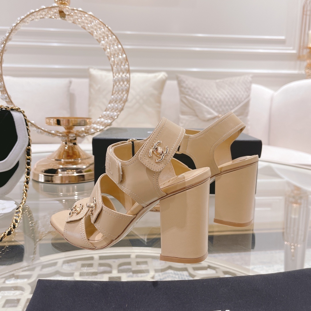 Pair of Chanel beige leather block heel sandals with gold CC logo hardware and branded ankle straps displayed on a glass table. - Hình 7
