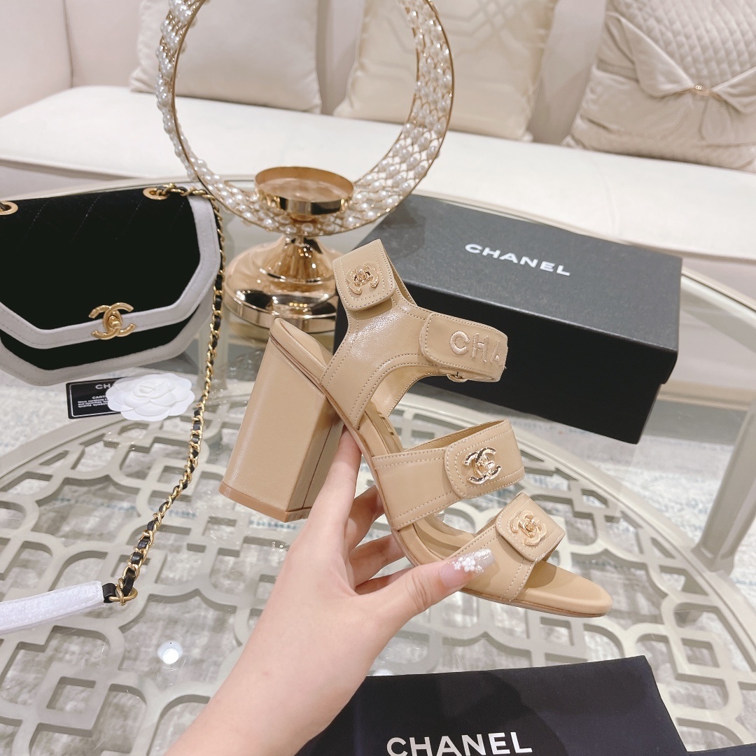 Pair of Chanel beige leather block heel sandals with gold CC logo hardware and branded ankle straps displayed on a glass table. - Hình 5