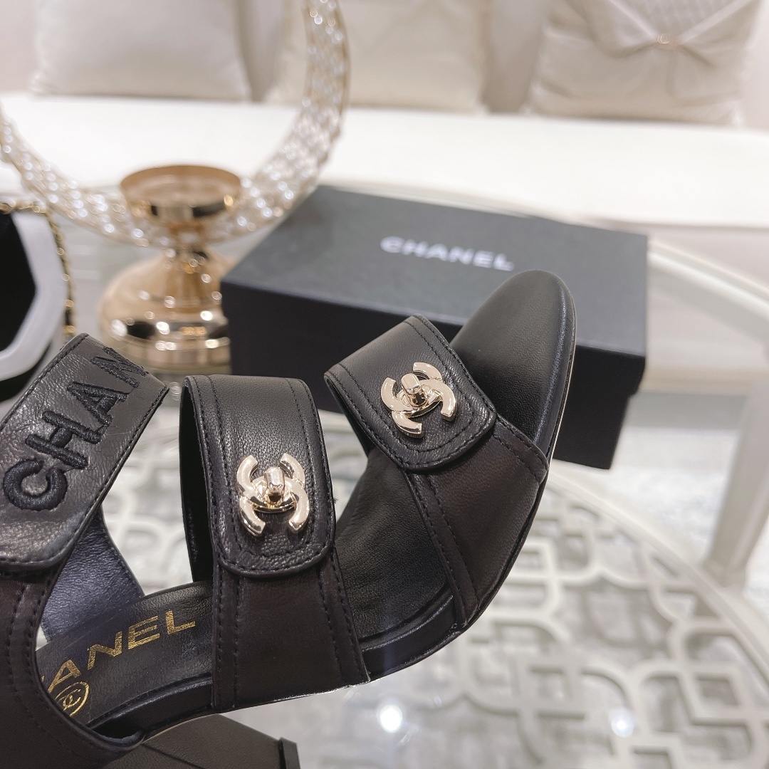 Pair of luxury black Chanel block heel sandals with gold CC logos and triple straps on a glass table - Hình 8