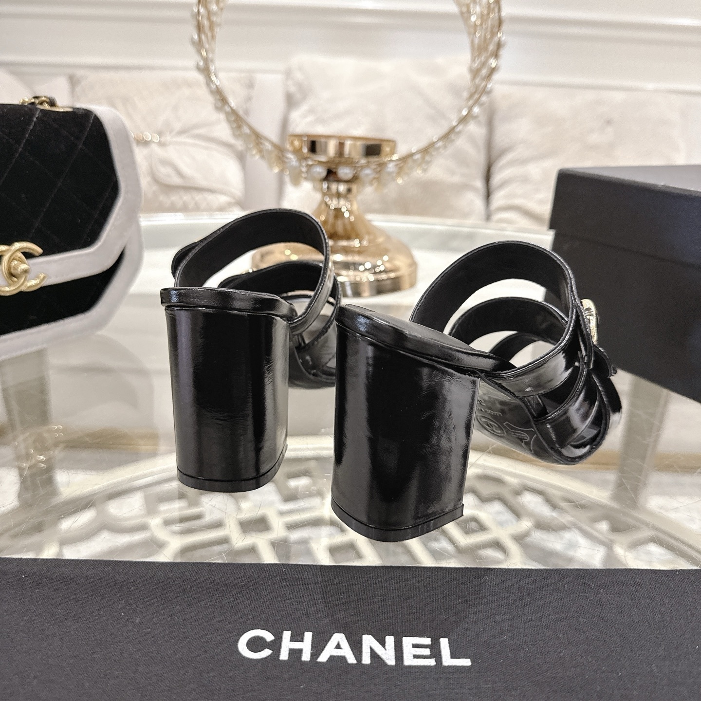 Luxury black patent leather sandals with triple straps and gold CC logo buttons on a designer glass table background. - Hình 8