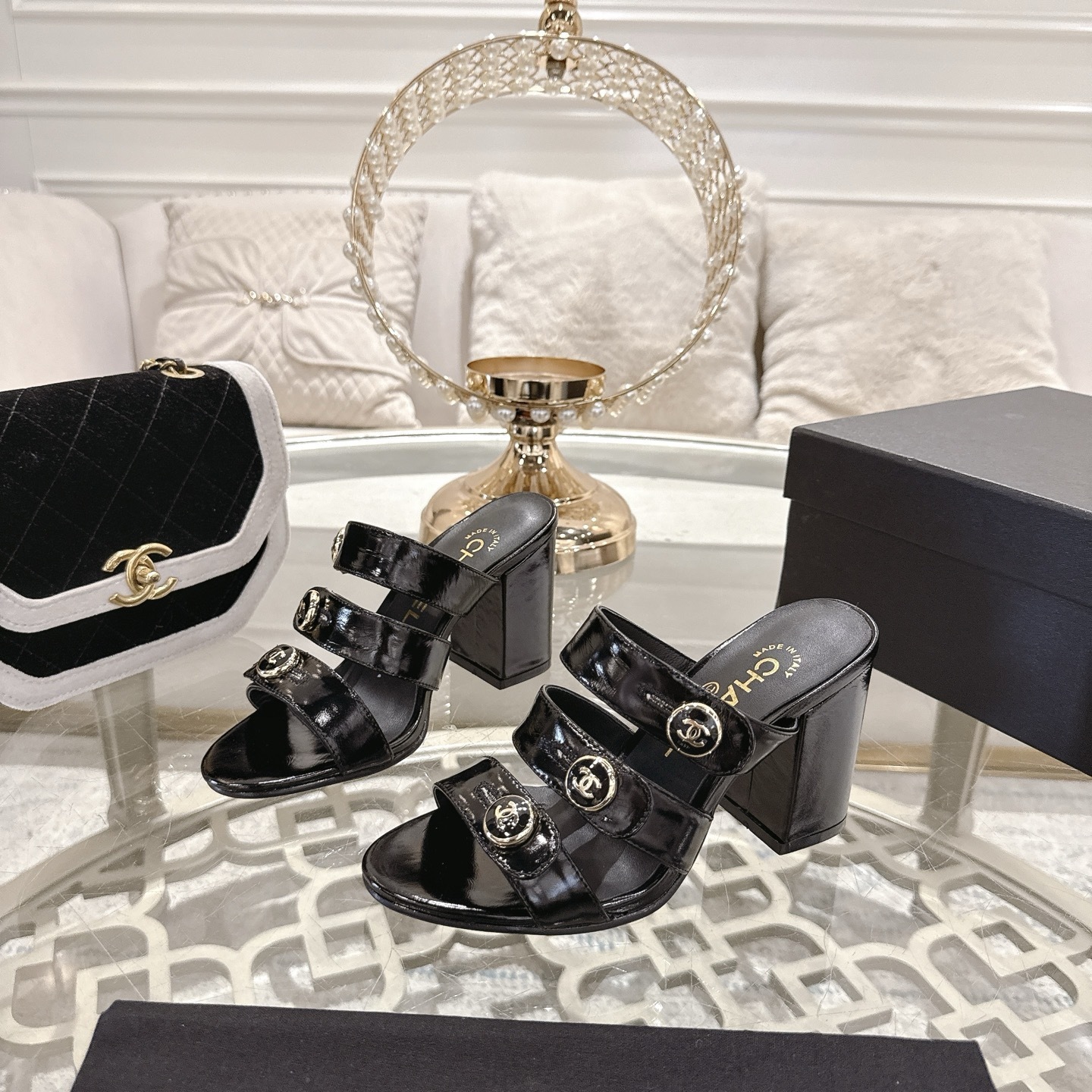 Luxury black patent leather sandals with triple straps and gold CC logo buttons on a designer glass table background. - Hình 3