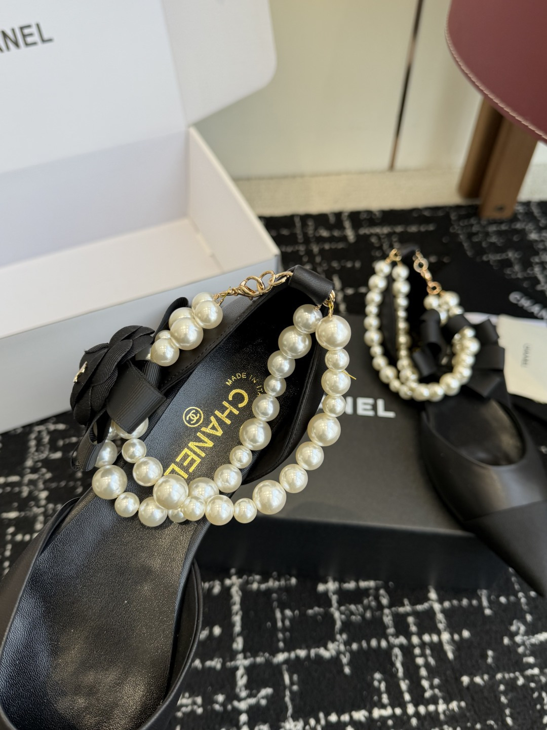 Pair of black Chanel leather pointed-toe flats featuring double pearl ankle straps and black camellia flower details with gold CC logo. - Hình 6