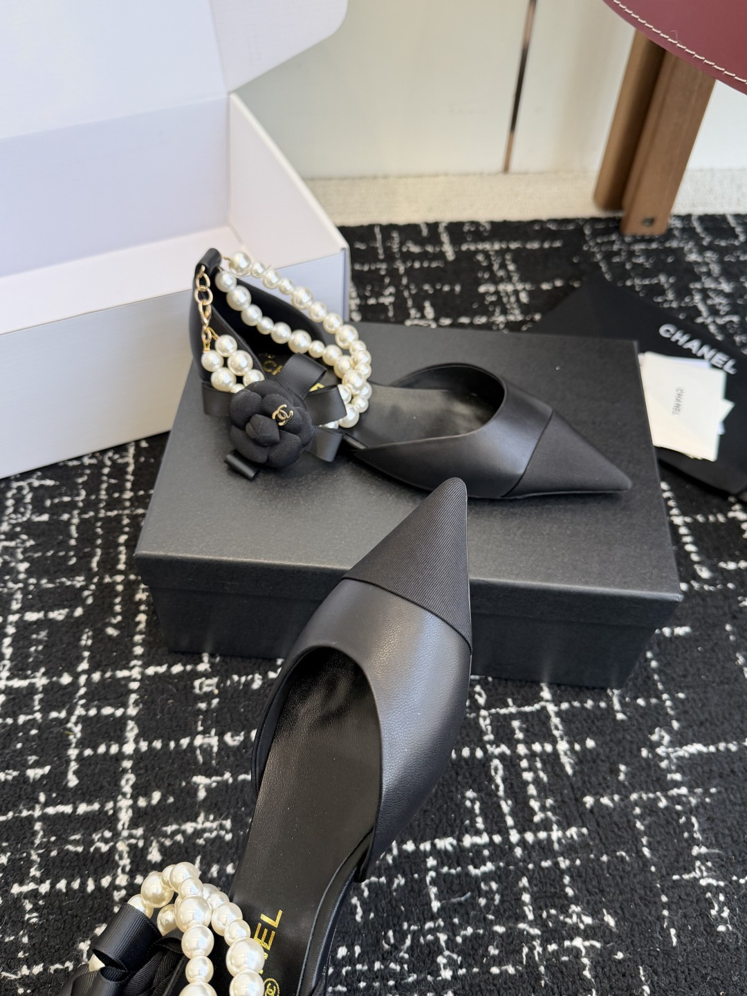 Pair of black Chanel leather pointed-toe flats featuring double pearl ankle straps and black camellia flower details with gold CC logo. - Hình 5