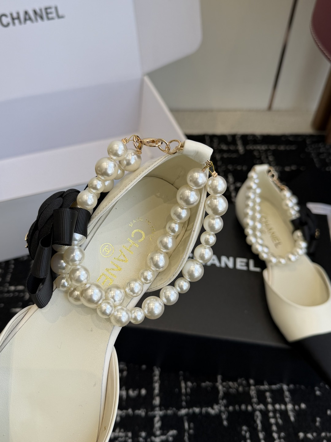 Chanel two-tone cream and black pointed-toe flats with double-strand pearl ankle straps and a black camellia flower detail. - Hình 7