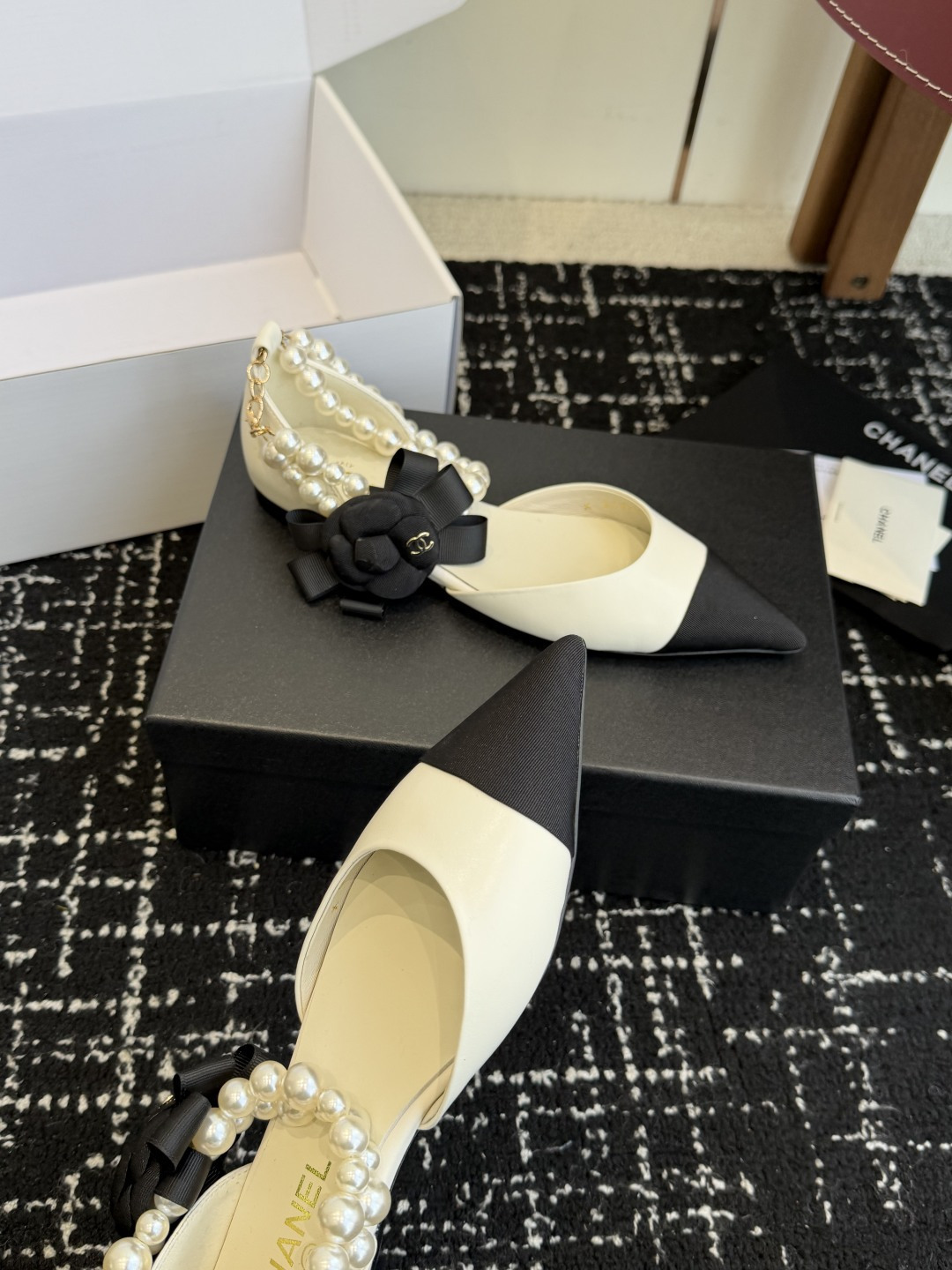 Chanel two-tone cream and black pointed-toe flats with double-strand pearl ankle straps and a black camellia flower detail. - Hình 5
